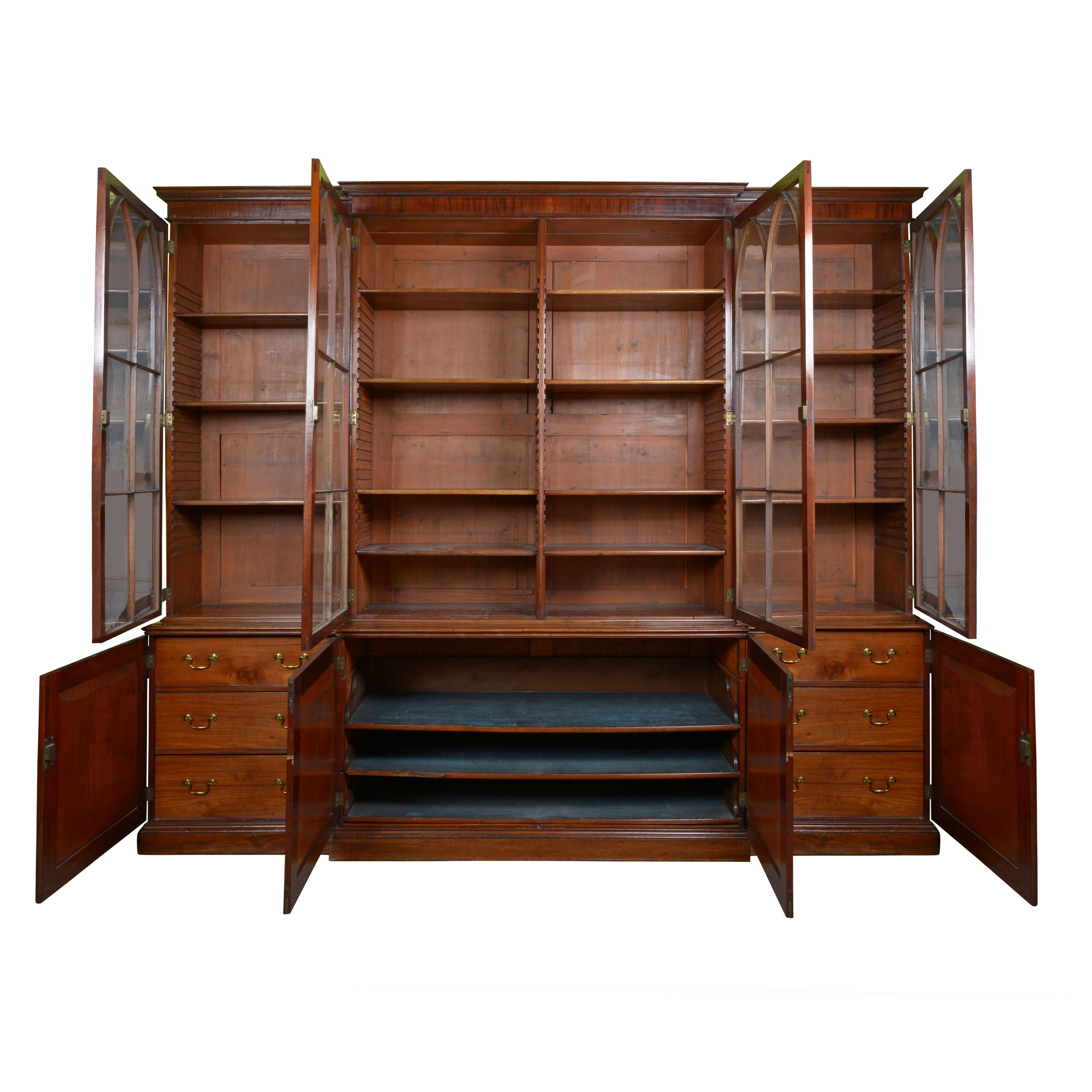 The upper section with four glass front doors opening to adjustable shelves; the lower part fitted with paneled doors opening to drawers and sliding trays.