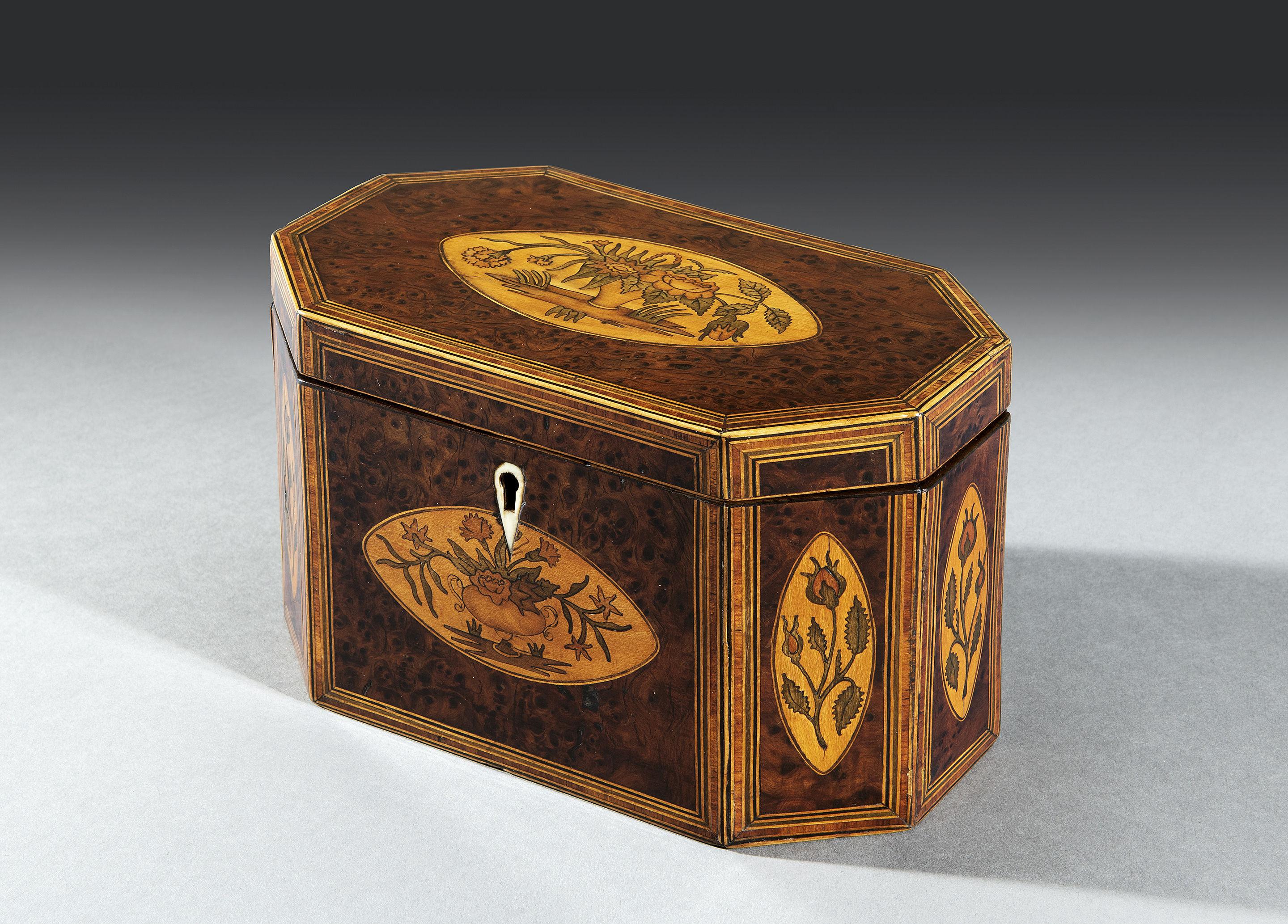 The burr yew octagonal top is triple banded and crossbanded with tulipwood, sycamore, boxwood and ebony stringing. The top is embellished with an oval inlaid floral marquetry bouquet design. This intricate banding is repeated on each side of the