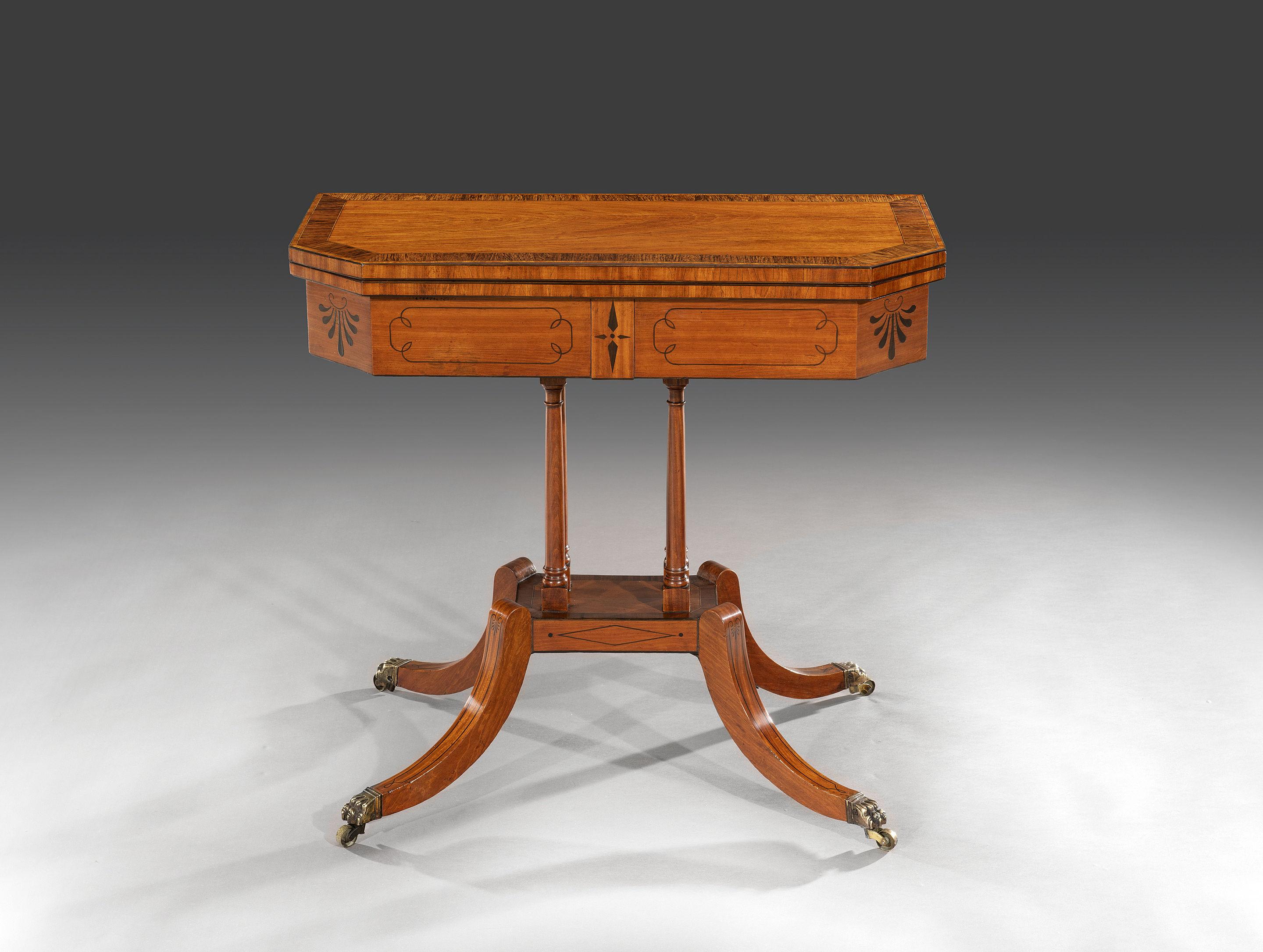 The rectangular top with canted corners is highly figured in West Indian satinwood and cross banded in rosewood and strung with boxwood and ebony. The top opens and swivels round to lay flat to reveal a green baize playing surface above a deep