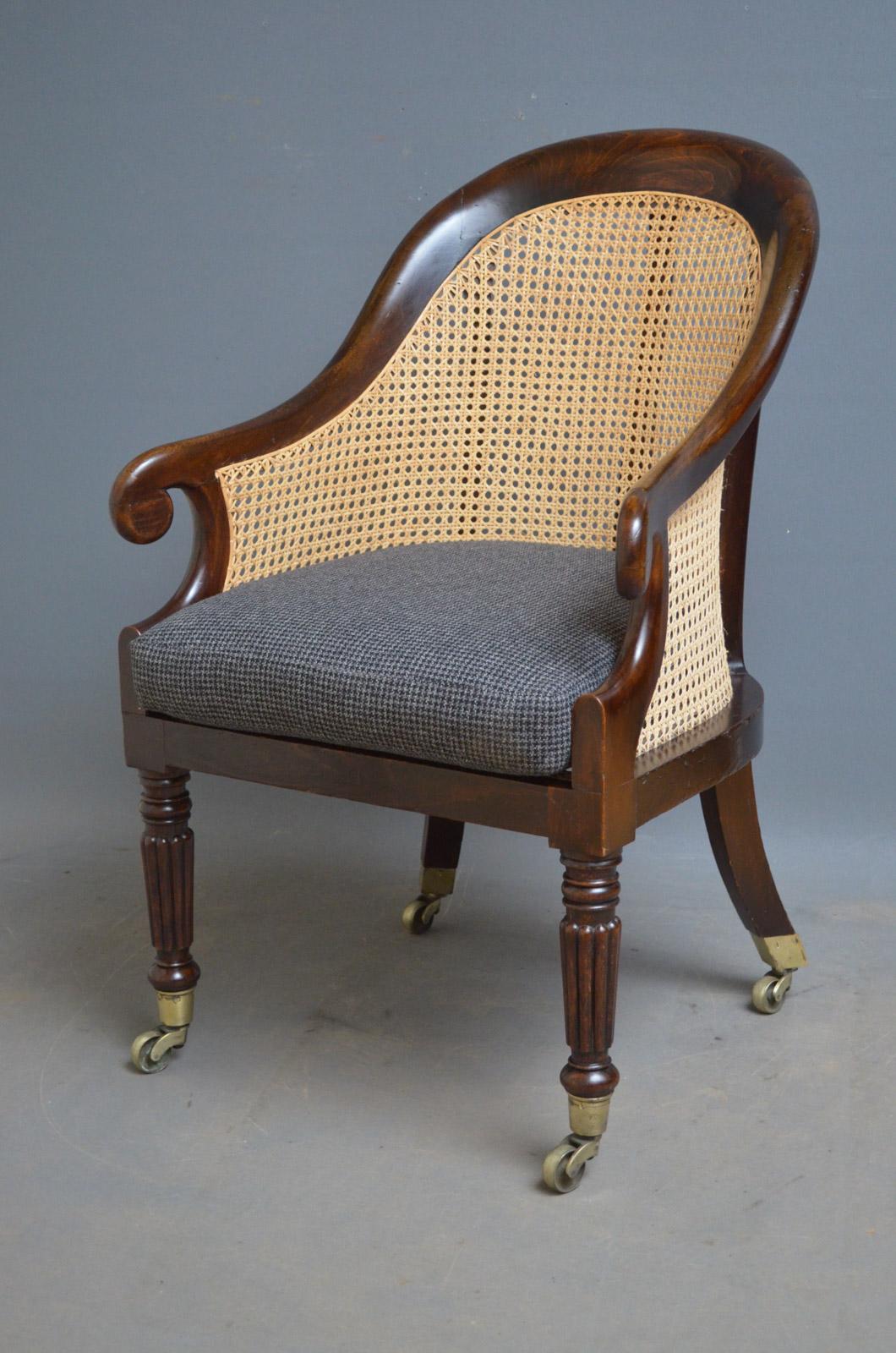 Sn4031 Georgian simulated rosewood bergère library chair, having curved top rail with scrolled arms caned back and seat with generous cushion, all standing on turned and fluted legs terminating in original brass castors. This antique armchair is in
