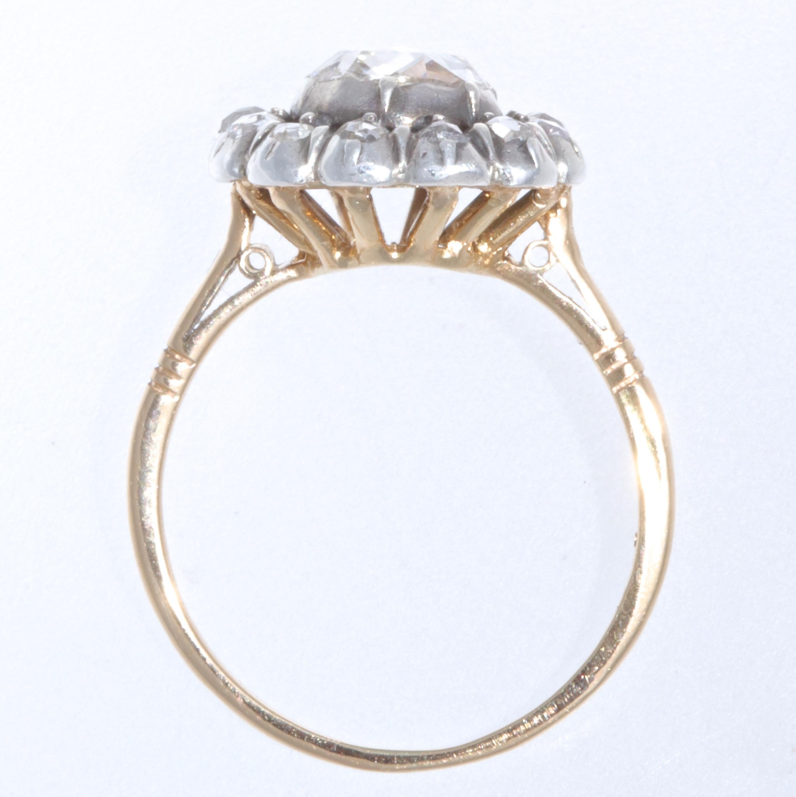 The cluster ring is from the late Georgian era. The cluster is original, the ring shank was added later. Featuring a rose cut diamond approximately 0.90 carats, G-H color SI2 clarity. The stone is in a foiled, closed back, silver collet bezel