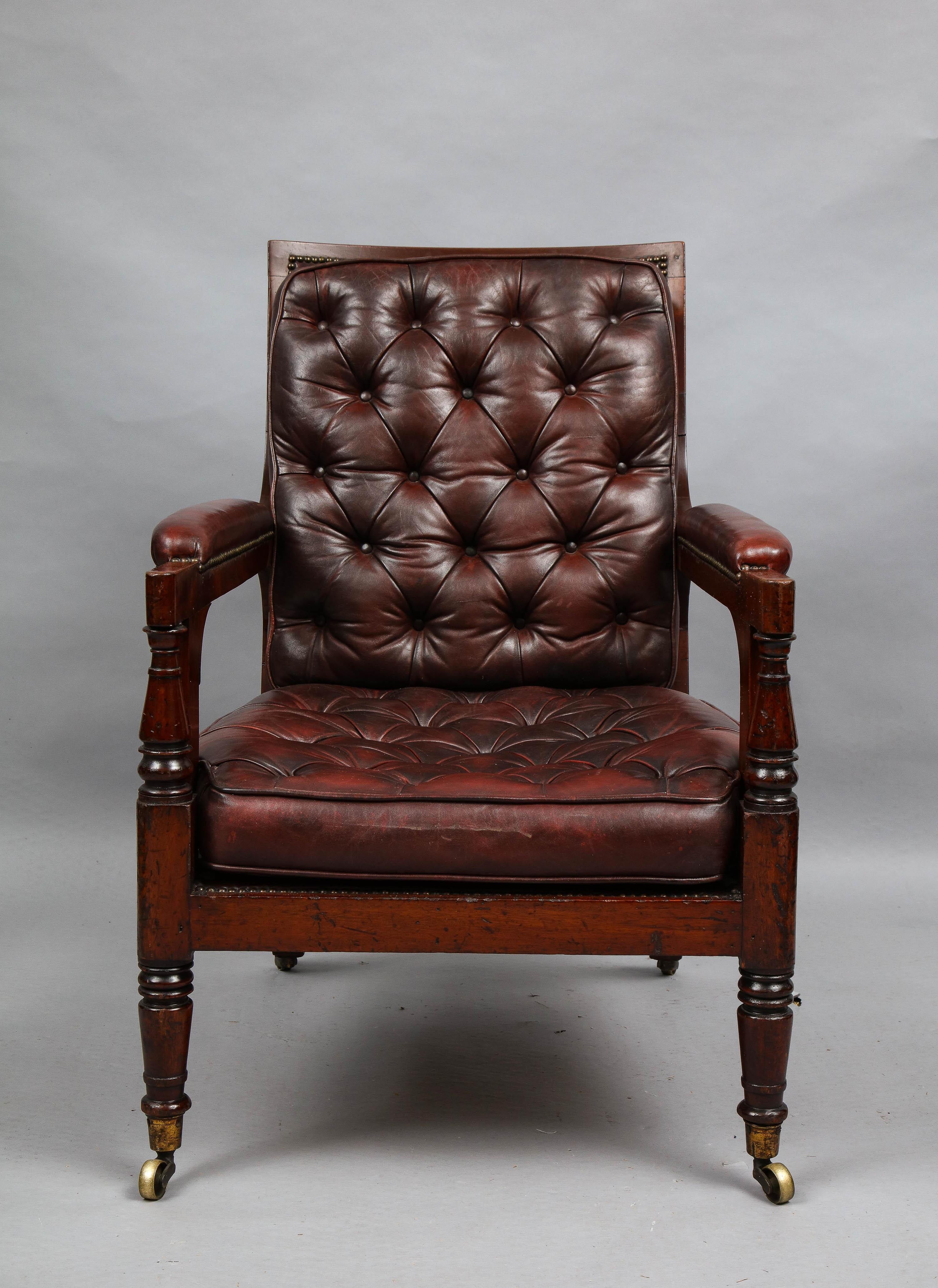 Good early 19th century mahogany library chair of good size and proportion having burgundy leather upholstery, the back with deep buttoning, while the loose cushion seat has shallow tufts over caned support, the whole with good rich color, the arm
