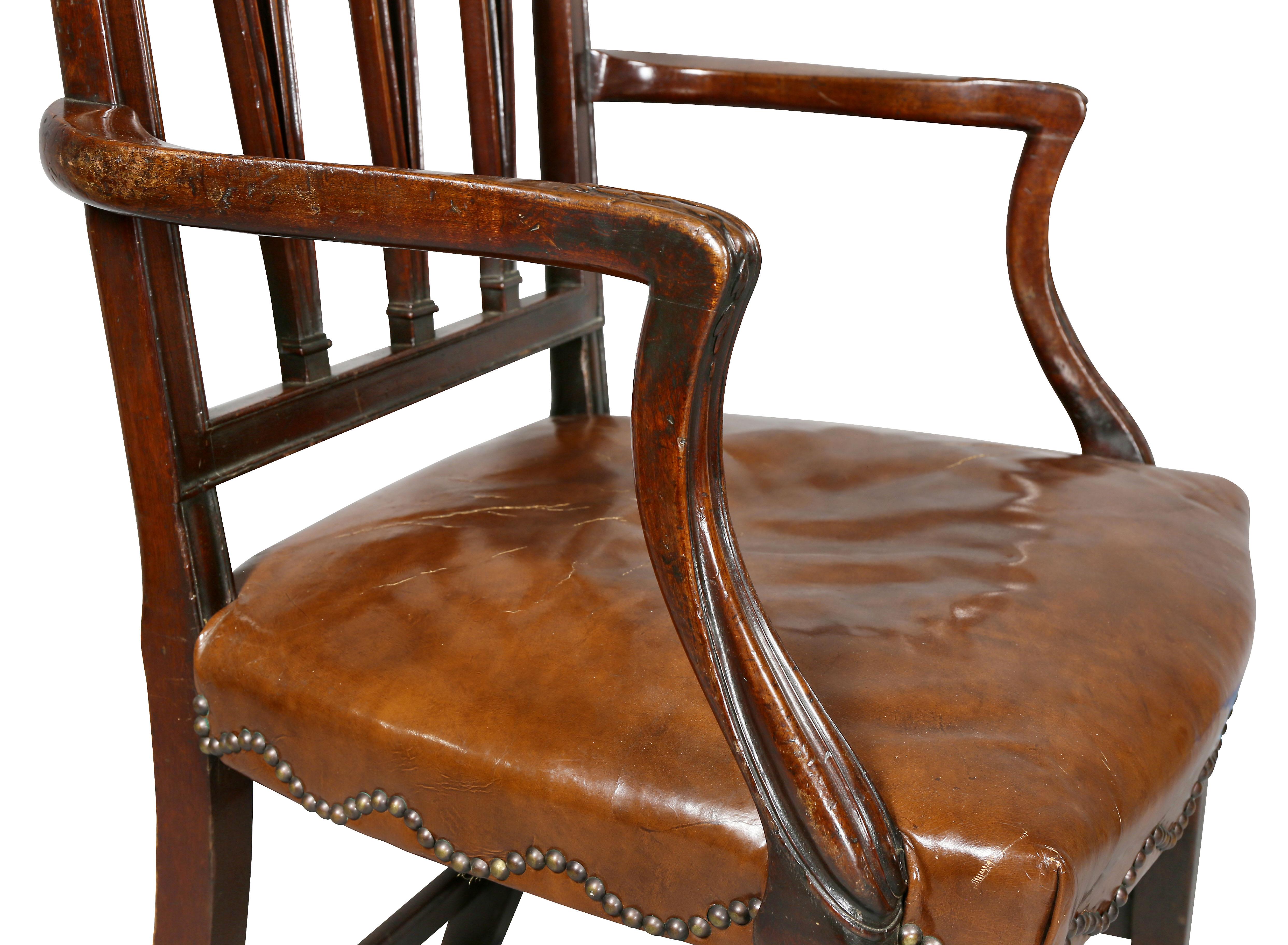 Sheraton form of large scale with carved arched back with three pierced splats, arms joining a brown leather seat, square tapered legs, stretchers.