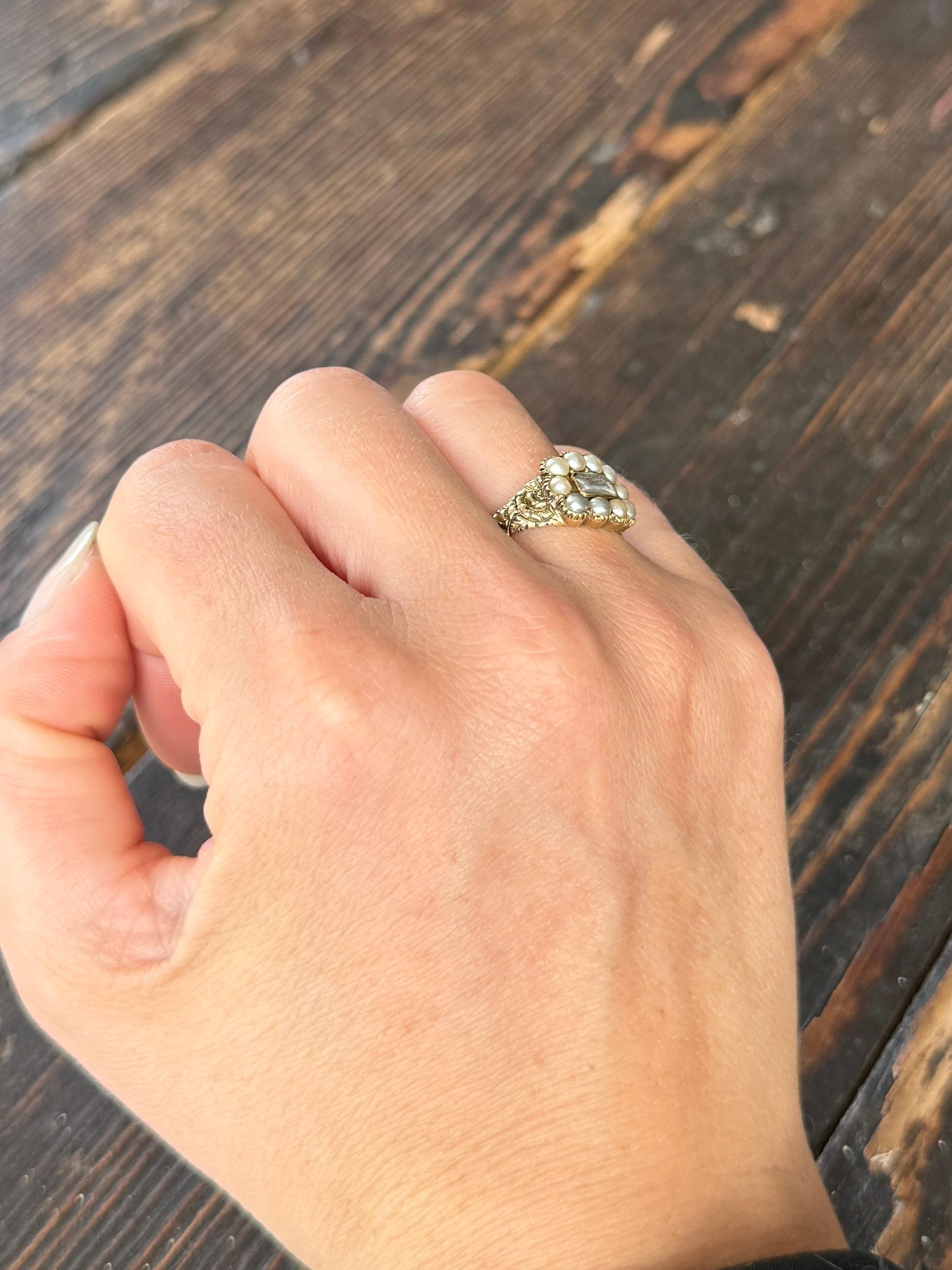 This lovely example of a late Georgian mourning ring holds a weave of hair behind crystal which sits on the most beautiful shoulders. The shoulders feature a raised flower pattern and the ring is modelled out of 9ct gold.

Ring Size: M 1/2 or 6