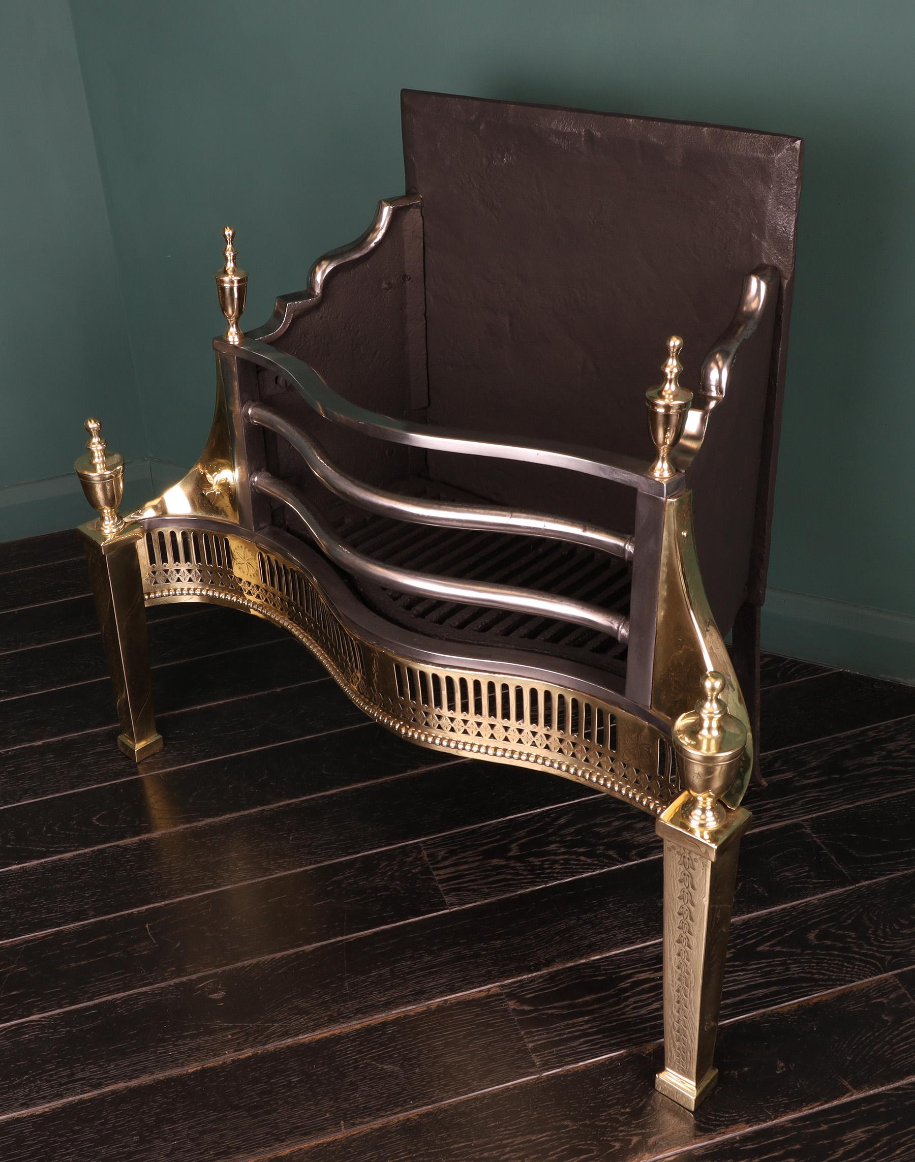 A late Georgian brass & steel serpentine fire grate. The railed basket supported by engraved tapered uprights on plinthed feet. The fluted frieze with fine delicate floral engraving set over beaded moulding. Intricate engraving to wings and urn