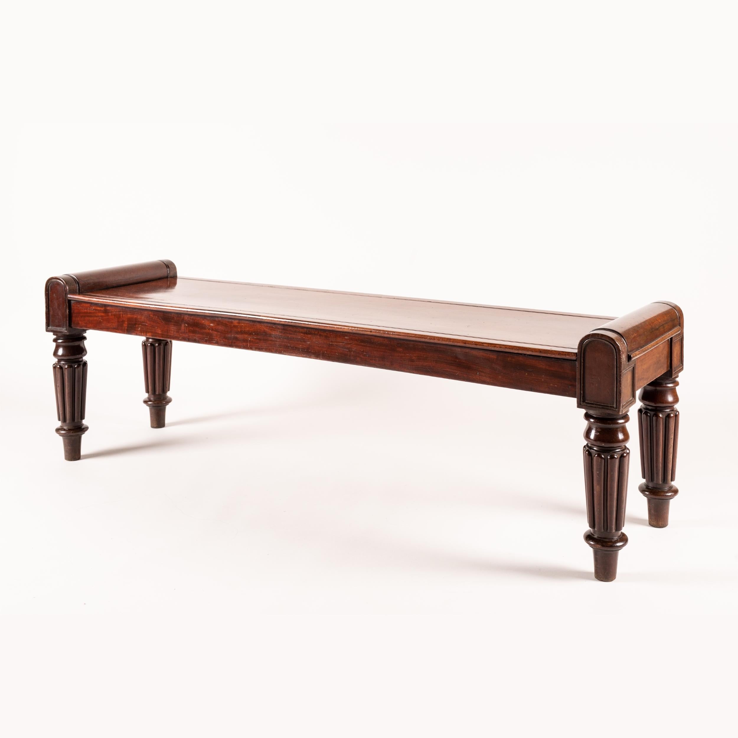 A late Georgian Period hall bench

Constructed from well-figured San Domingo mahogany, the bench supported on tapering ring-turned and lobed legs, terminating in rounded capitals, with the seat with carved recessed details.
English, circa