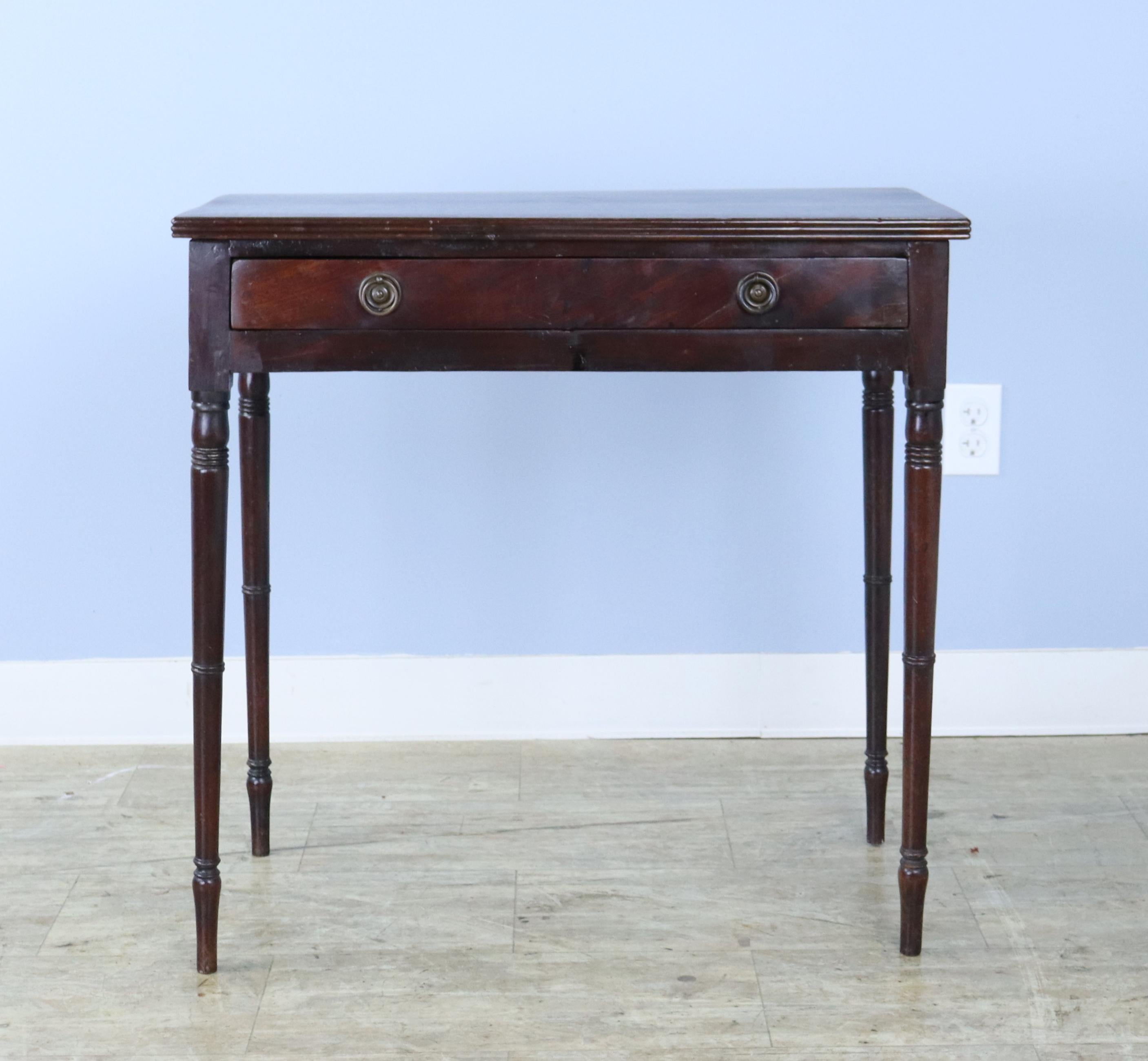 An elegant dark mahogany side table with slim turned legs and a single drawer.   Lovely period appropriate reeded edges on the top.