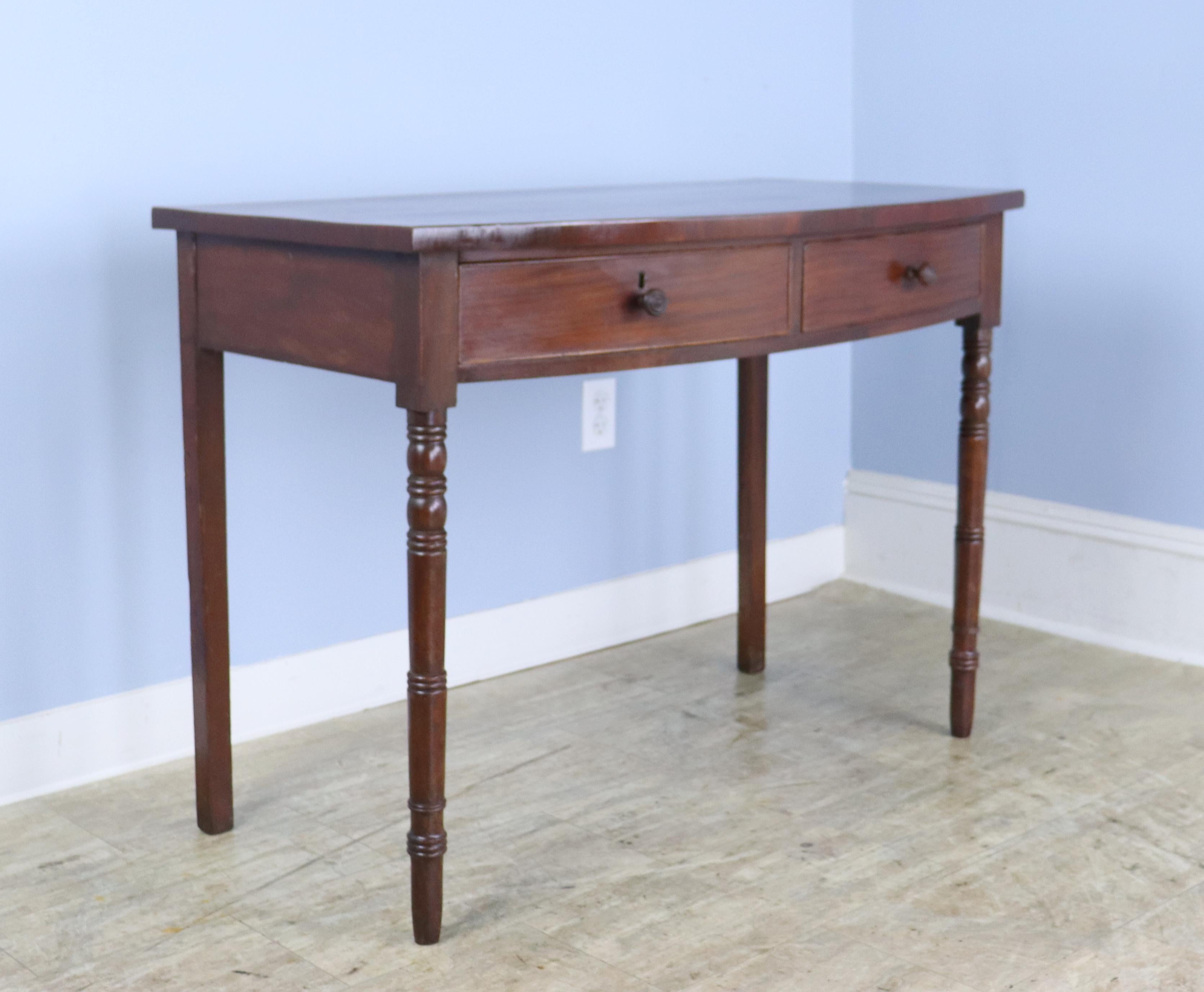 A refined late Georgian serving table or desk in warm mahogany with delicate satinwood stringing around the top.  The two drawers close snugly and are in good condition, having retained their delicate cockbeading.  The slim turned legs complete the