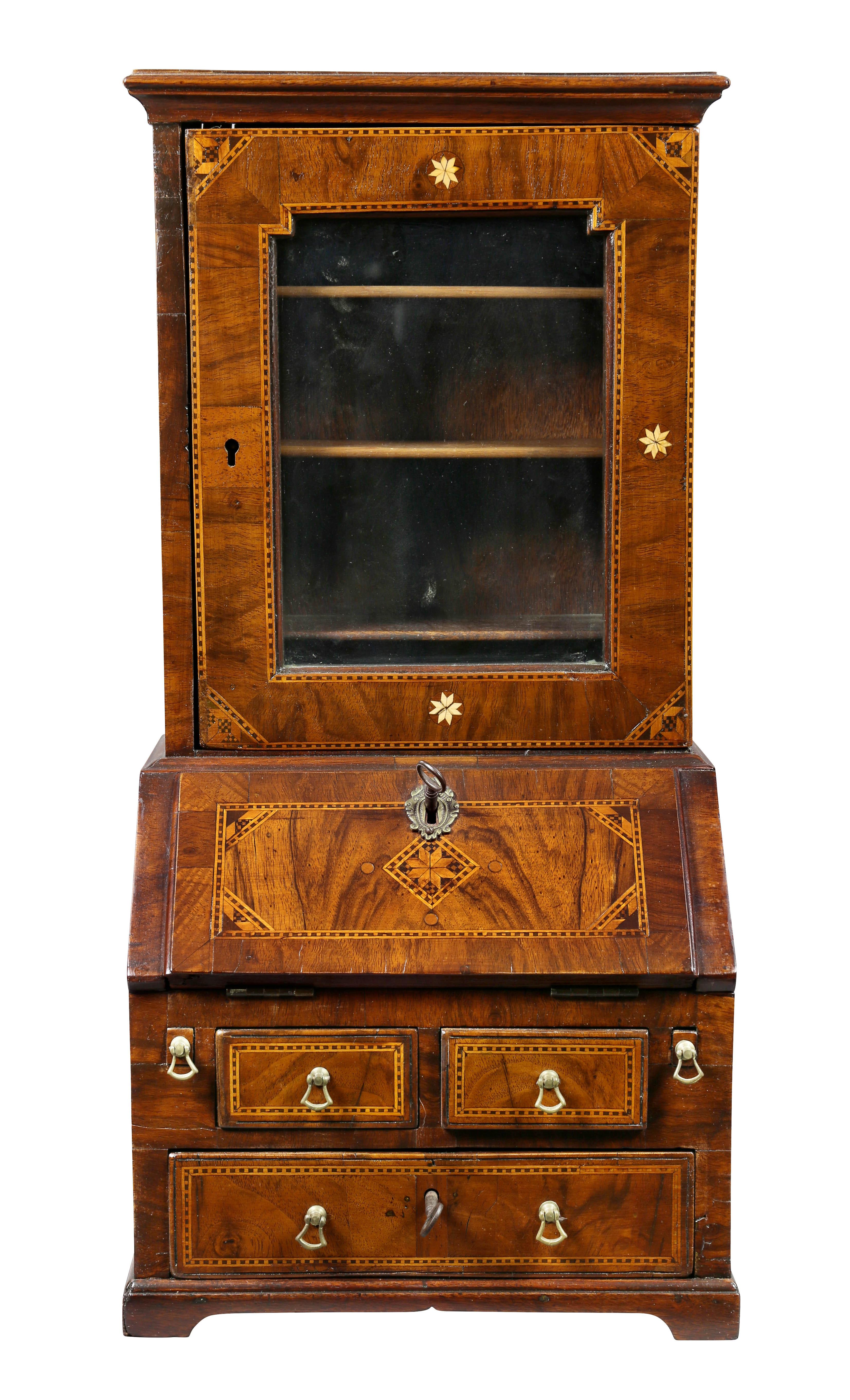 With a rectangular cornice over a single glazed door, the base with slant fold - down writing lid exposing a fitted interior over two short and a long drawer , bracket feet. With various inlays. Estate of Nancy Carroll Draper, Cody Wyoming.