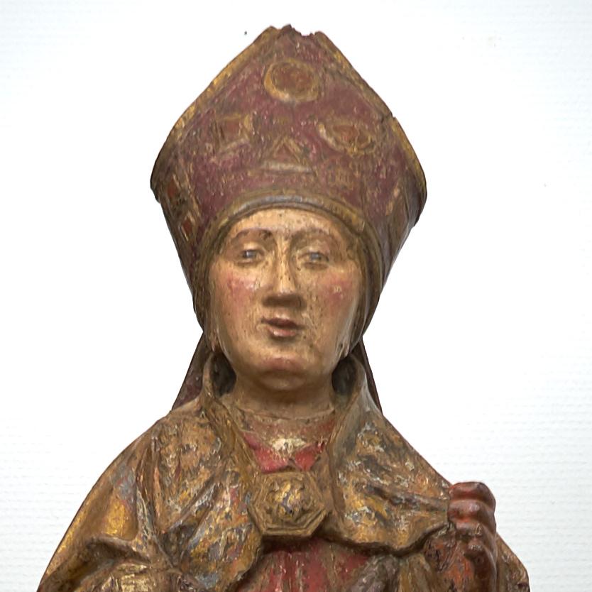 A (probably French) Late Gothic ( circa 1500 ) oak figure of a holy bishop executed in full round depicted standing in hieratical frontal pose with fine facial features, well decorated mirte and draped bishop’s garment. The rests of the existing