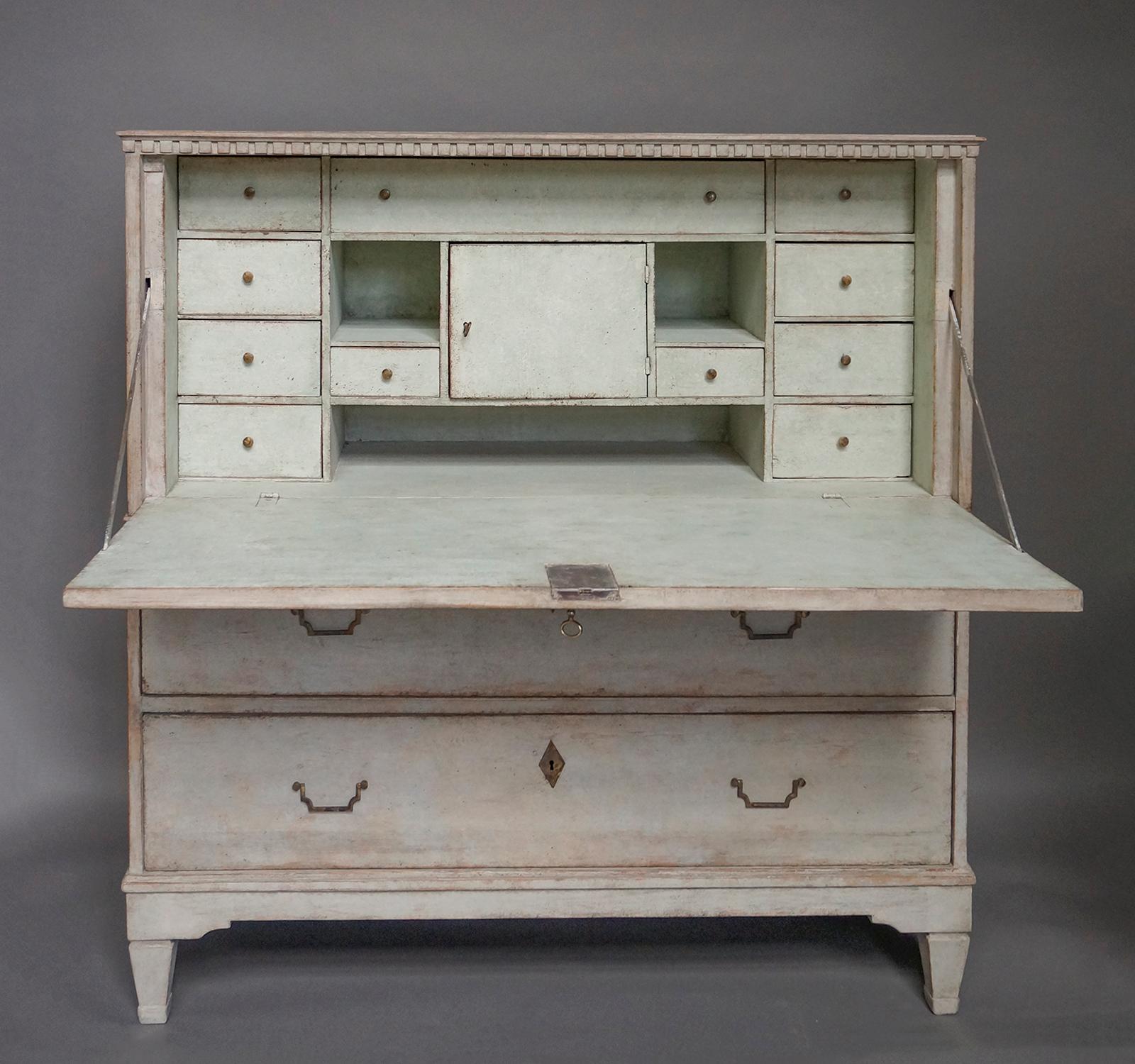 Period Gustavian fall-front writing desk, Sweden, circa 1820, with fitted interior. The front panel with reeded detail opens to reveal banks of drawers and a central compartment. Below the writing surface are two full-width drawers. Dentil molding