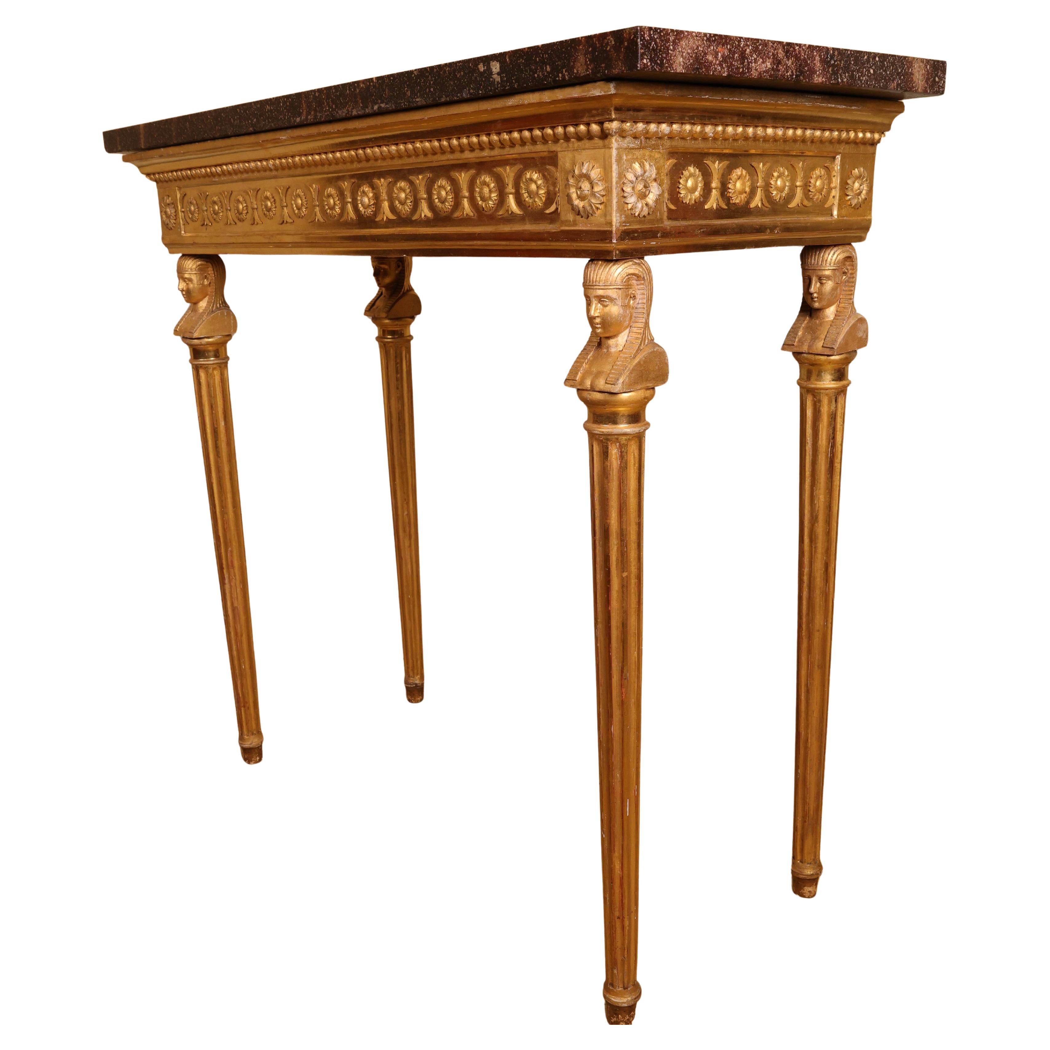 A high-class late Gustavian gilt console table made in Stockholm, Sweden around 1800. The legs feature carved Egyptian-inspired heads and fluted details. The table's frieze is decorated with a carved bead border and floral motifs. The top is an