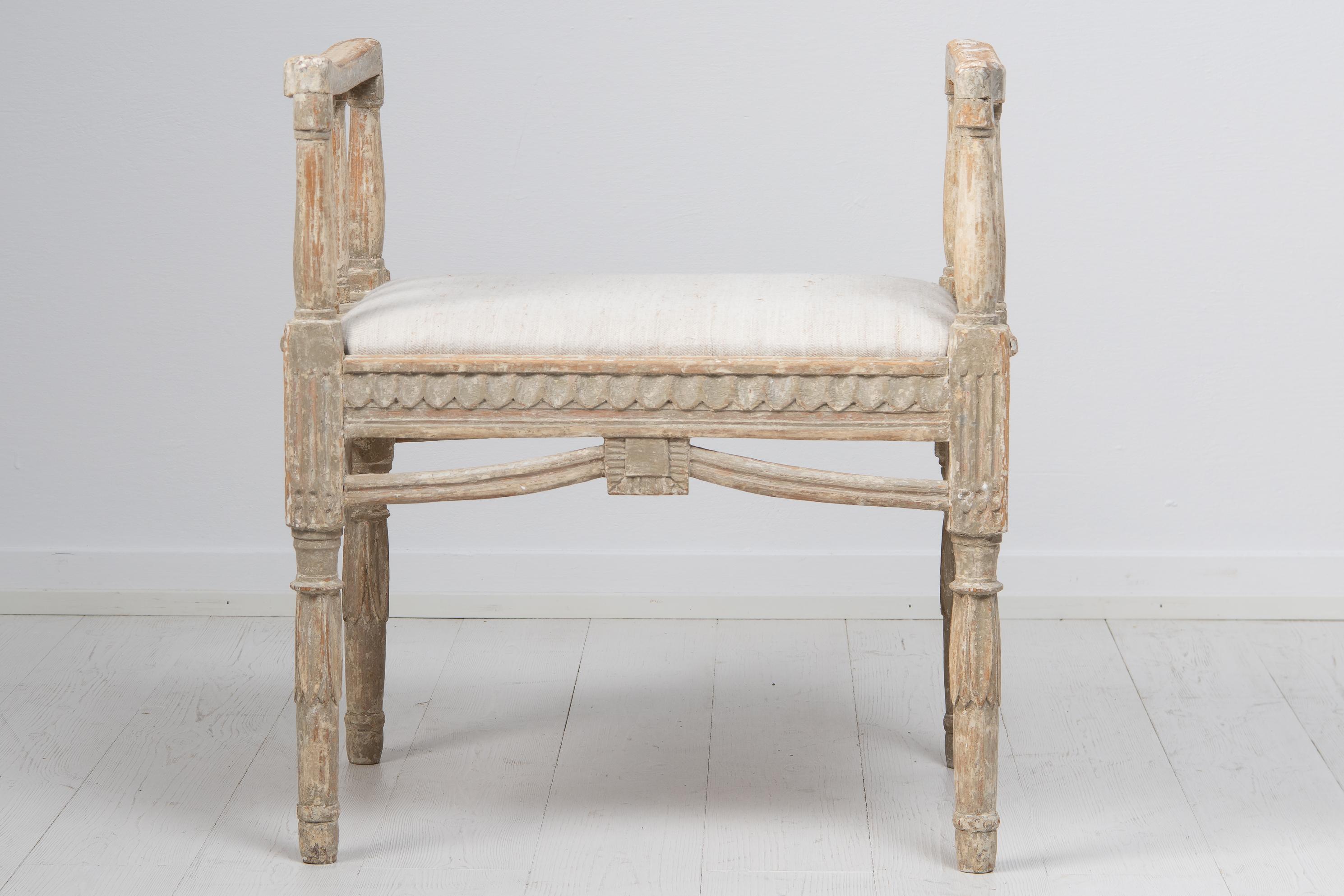 Swedish late gustavian tabouret or footstool from the years around 1790 to 1810. The tabouret is from Sweden and made in pine. This piece is made with armrests or handles on each side as well as a rich decor. The paint has been dry scraped by hand