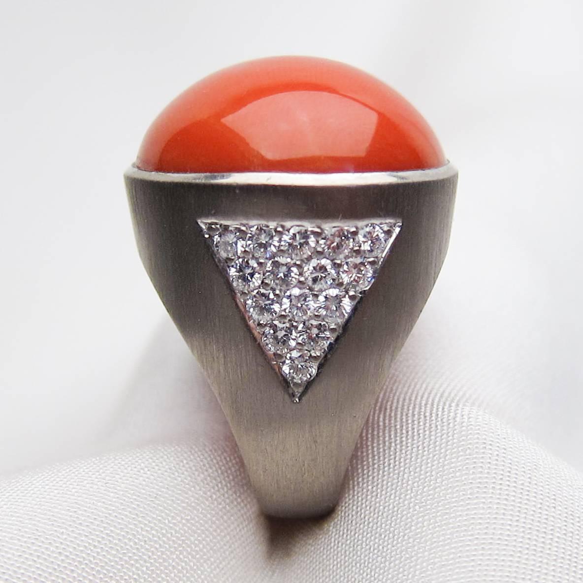Circa 1970s. This cool cocktail ring exudes the individuality that characterized 1970s fashion. The star of the show is a 39.80 carat orange-red coral cabochon set in 18KT white gold. Accenting one shoulder of the ring are 15 brilliant-cut diamonds