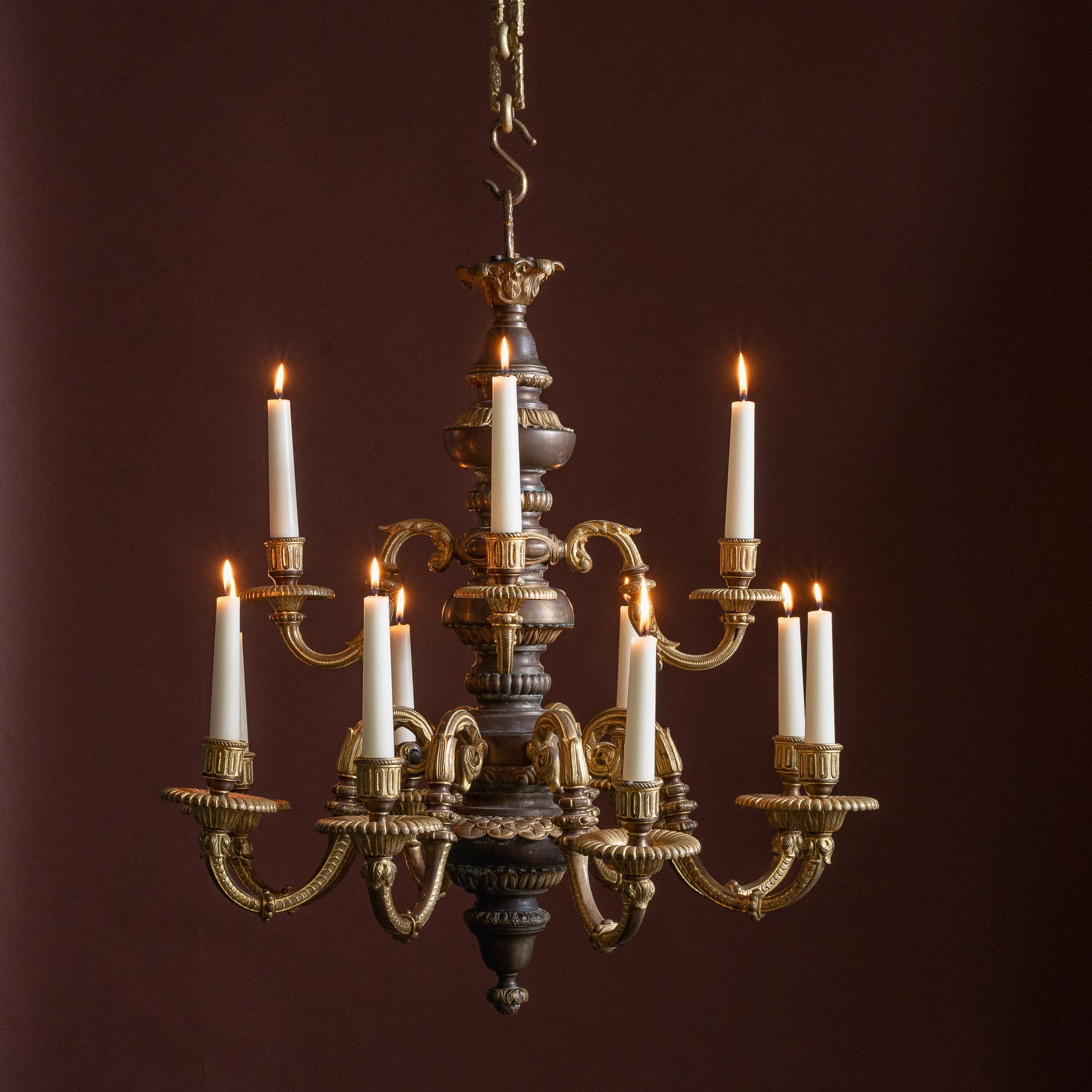 Lustre français en bronze patiné et doré de la fin du XIXe siècle  à douze branches, peut être raccordé à l'électricité si nécessaire (£750 GBP). Chaîne décorative et rosace de plafond d'origine incluses.

Dimensions :	66cm (26