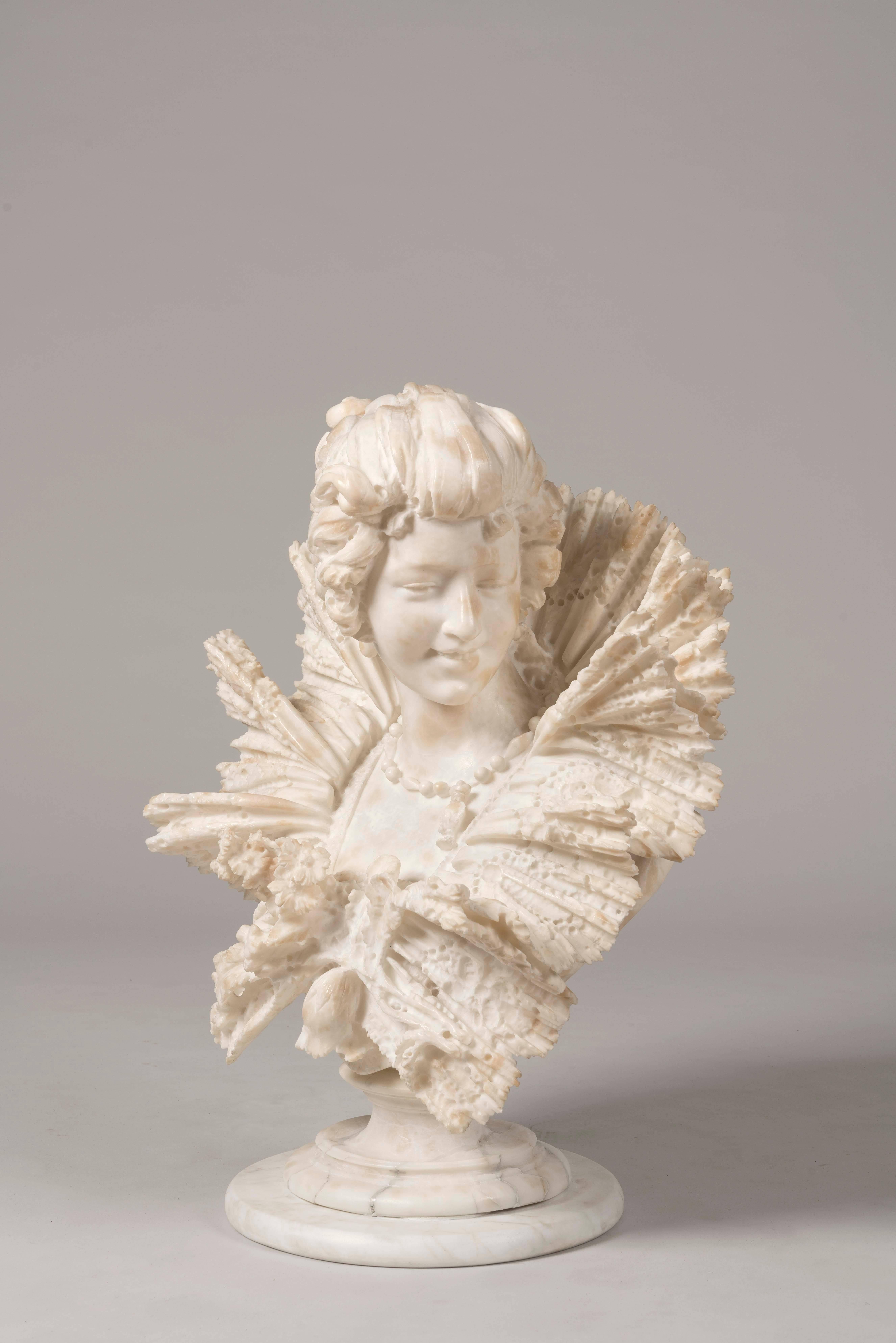 A Belle Époque beauty

A bust of a smiling maiden, carved from alabaster bianco, her coiffured hair in a chignon, wearing a square decollete dress with a pleated lace ruff showing a necklace sits on a circular lipped socle, set up a faux marble