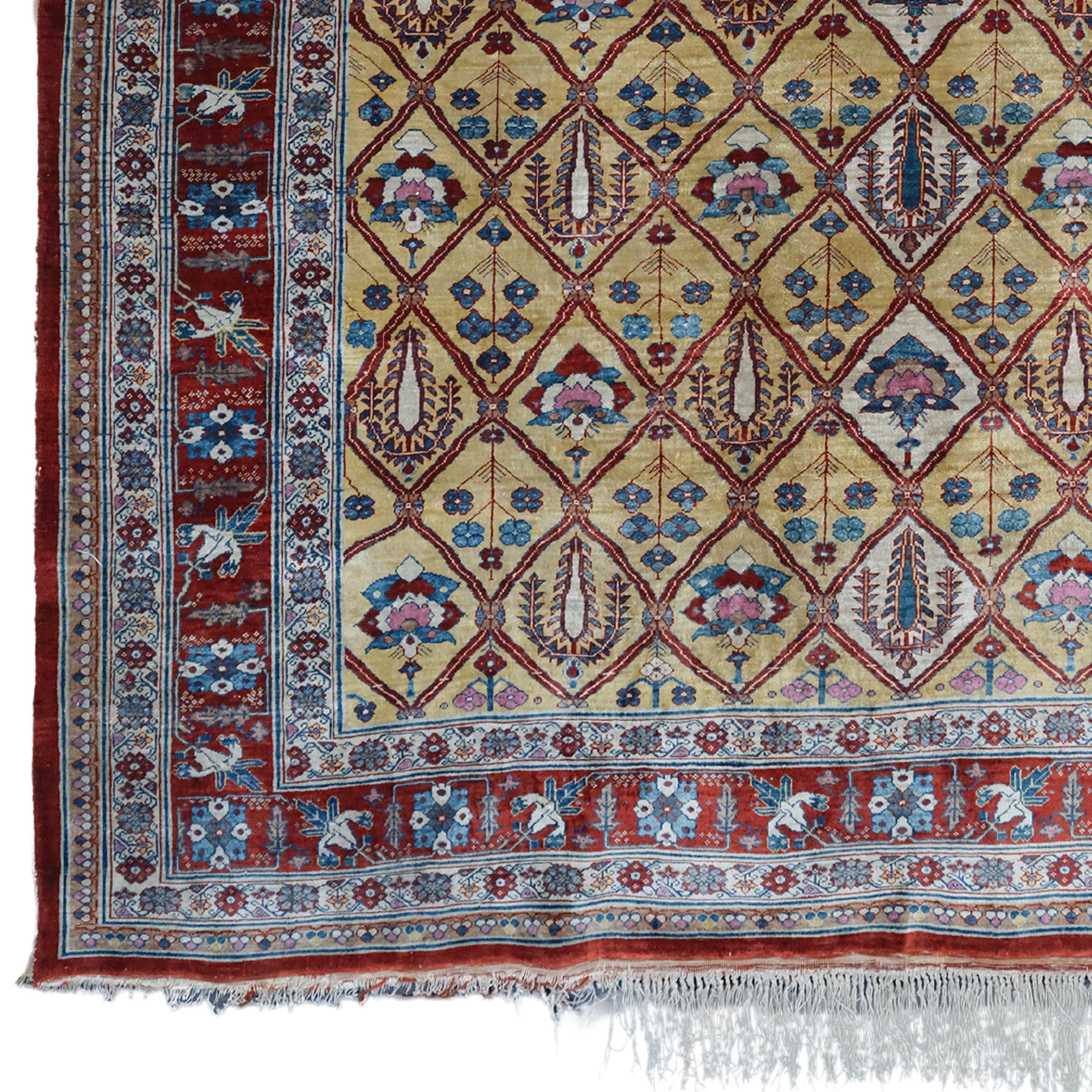 This antique Heriz rug is a hand-woven work of art from silk, dating back to the late 19th century. This carpet, decorated with rich geometric shapes and motifs, has a color palette dominated by red, blue and beige tones. The central area is