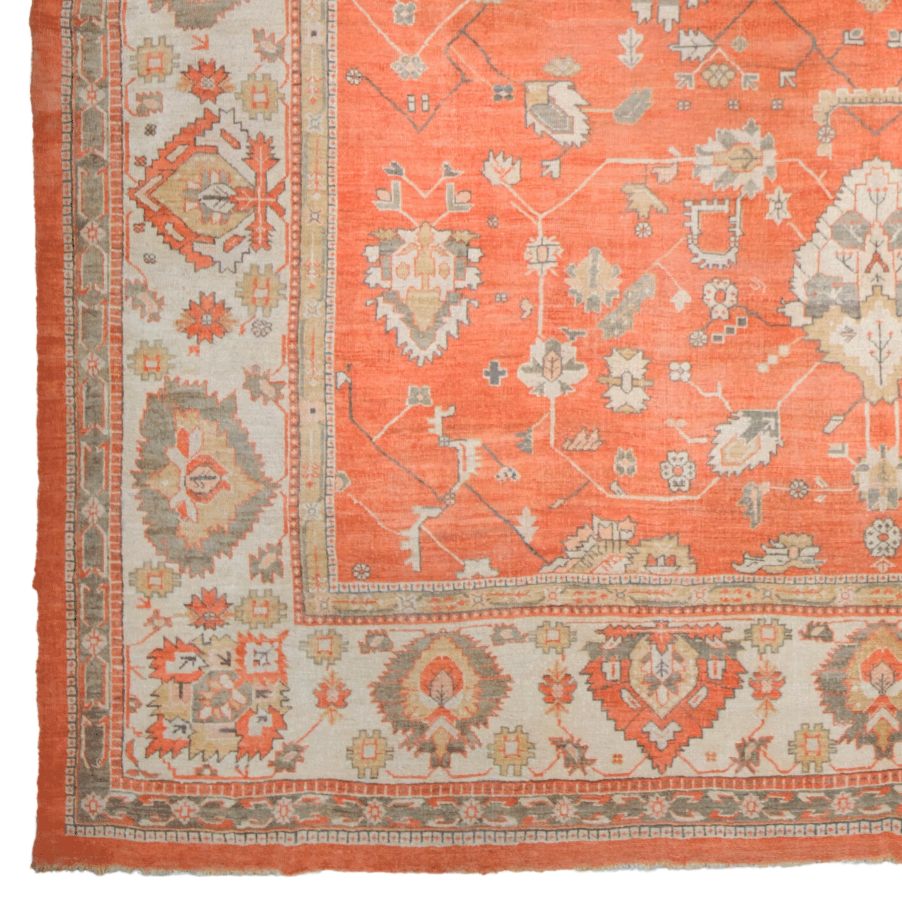 Questo antico tappeto Uşak presenta intricati motivi in toni chiari e scuri su uno sfondo arancione. Il tappeto presenta un medaglione centrale, staffe angolari e un bordo ornato con motivi geometrici e floreali ripetuti, che lo rendono un elemento