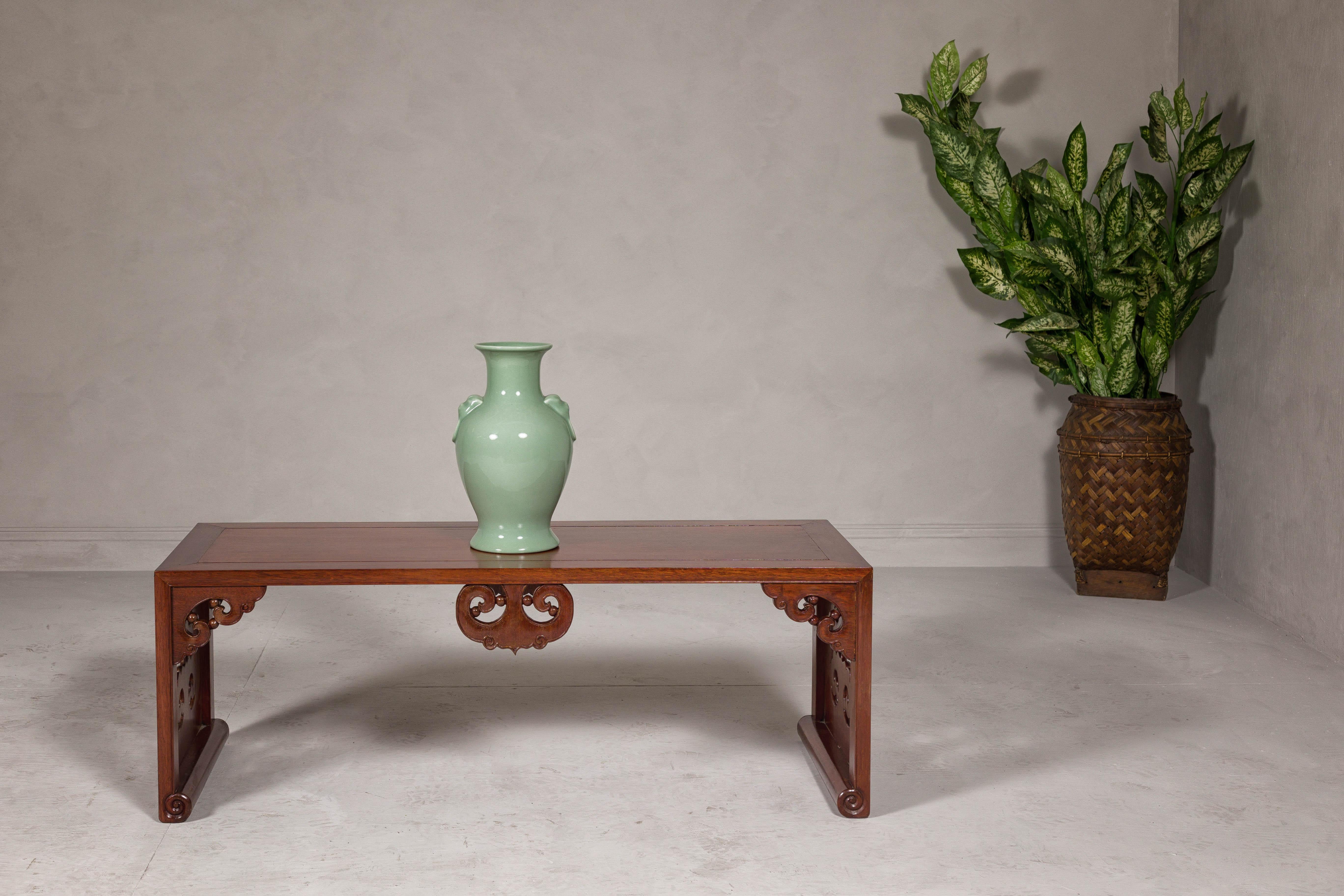 A late Qing Dynasty period brown lacquered coffee table from the early 20th century with openwork cloud motifs. Created during the late Qing Dynasty period, this exquisite brown lacquered coffee table from the early 20th century captures the essence
