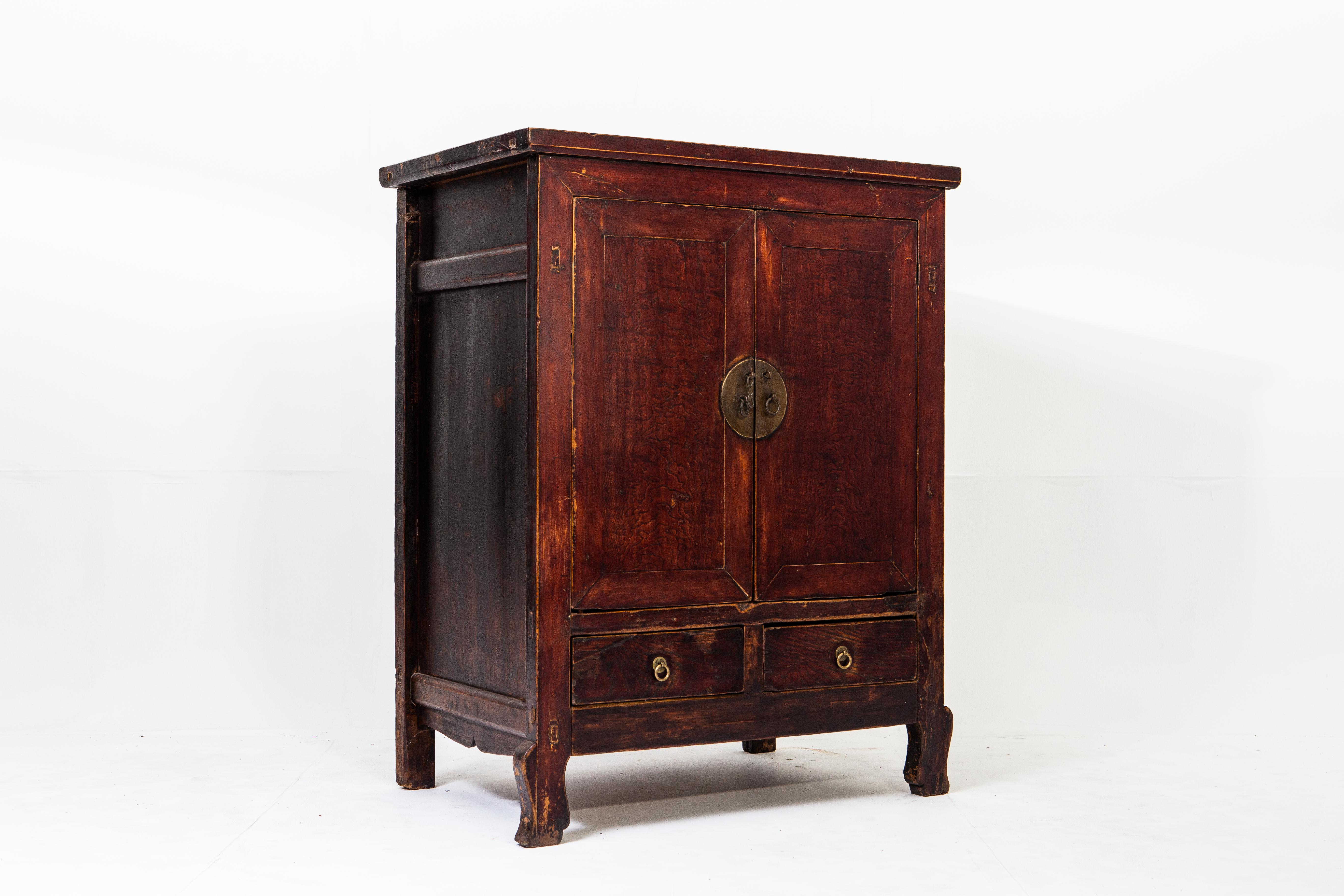 This cabinet is made of elm and dates to the late-Qing dynasty. The piece has a rich patina that emphasizes the grain of the wood. There is ample storage on the interior in addition to the two drawers at the base of the piece. Wear is consistent