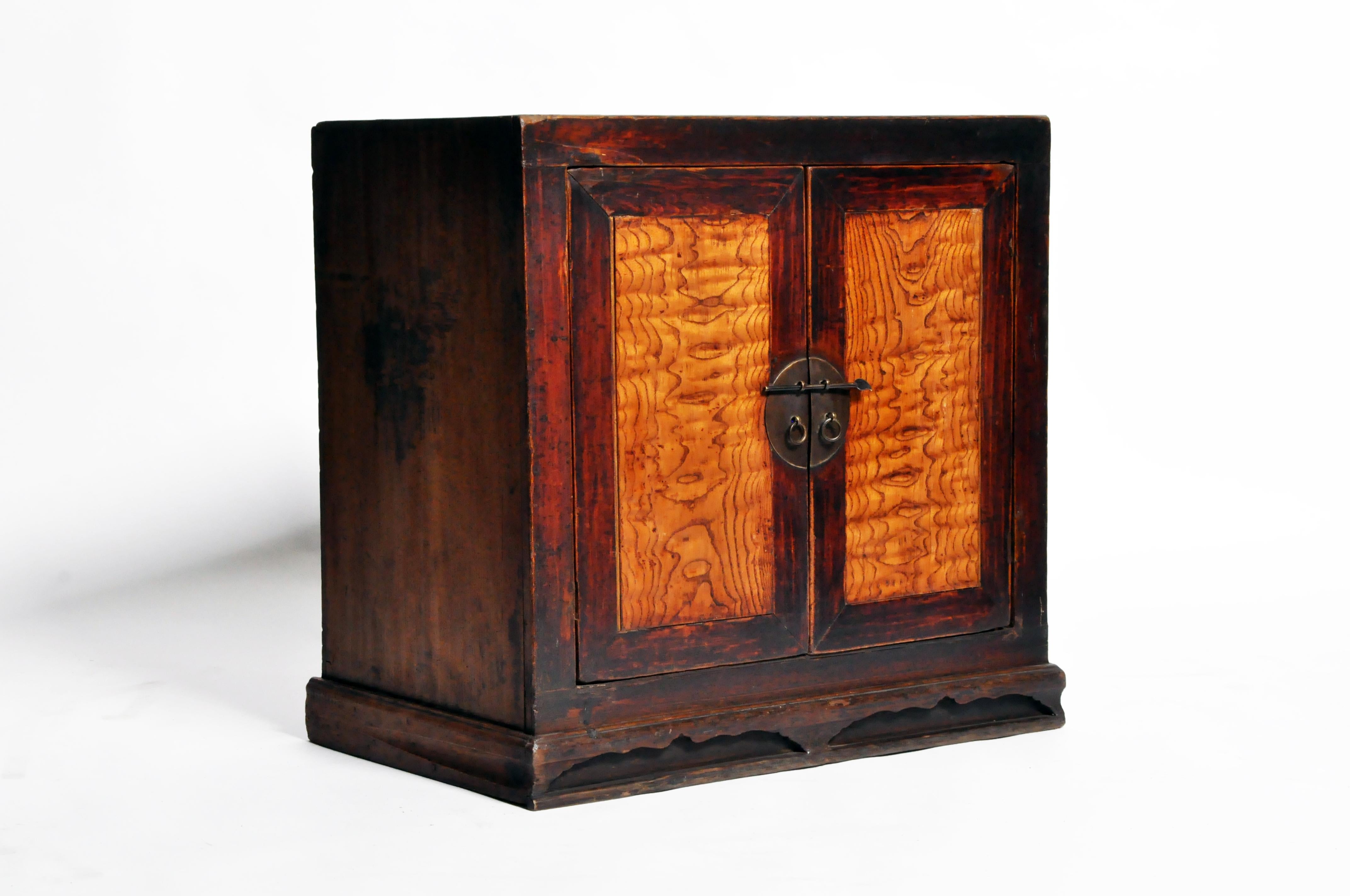 This Chinese storage chest dates to the late 1800s. The paneled door inserts and drawer fronts feature dramatically contrasting wood grain and moon-form escutcheon with ring pulls. Handsome lines continue throughout this storage chest, wear