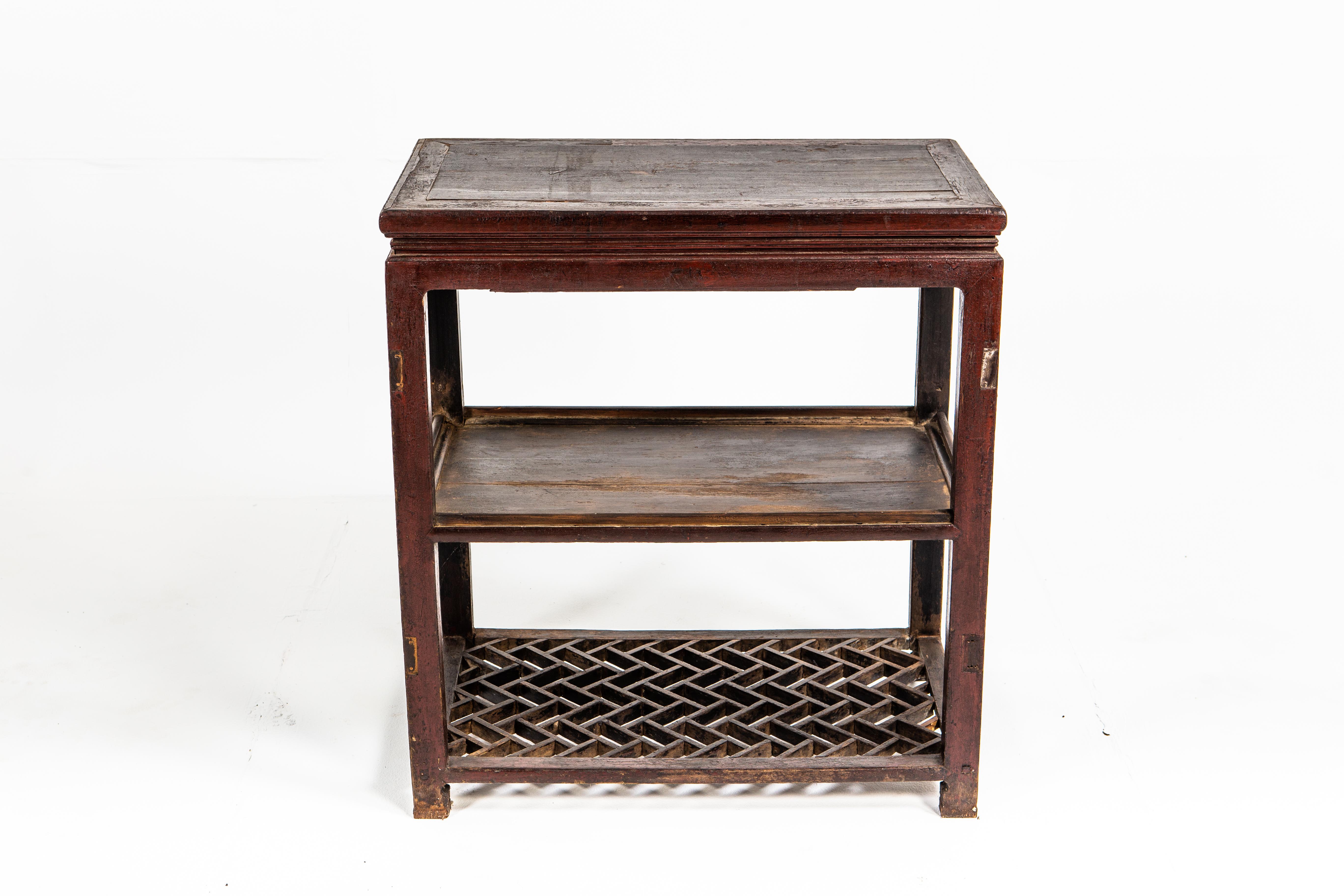 This late-Qing dynasty side table has a weathered lacquered finish, giving this piece a beautiful aged original patina. The table has two shelves, one of which features traditional latticework.