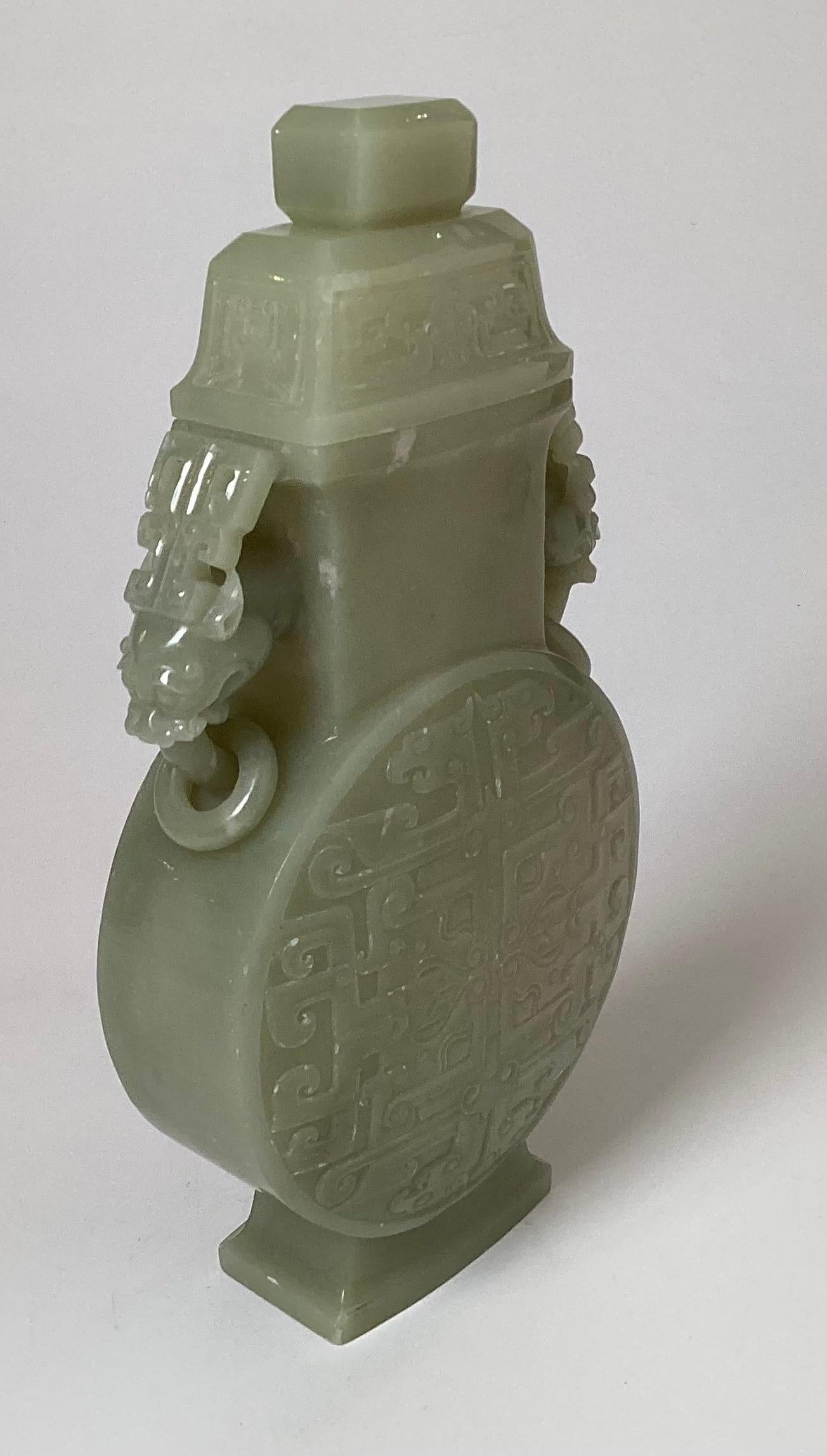 Early 20th Century intricately carved celadon vase with lid. The moon flask shape with dragon handles with rings. Incised on both sides with archaistic very detailed. 9.38 inches tall. 
