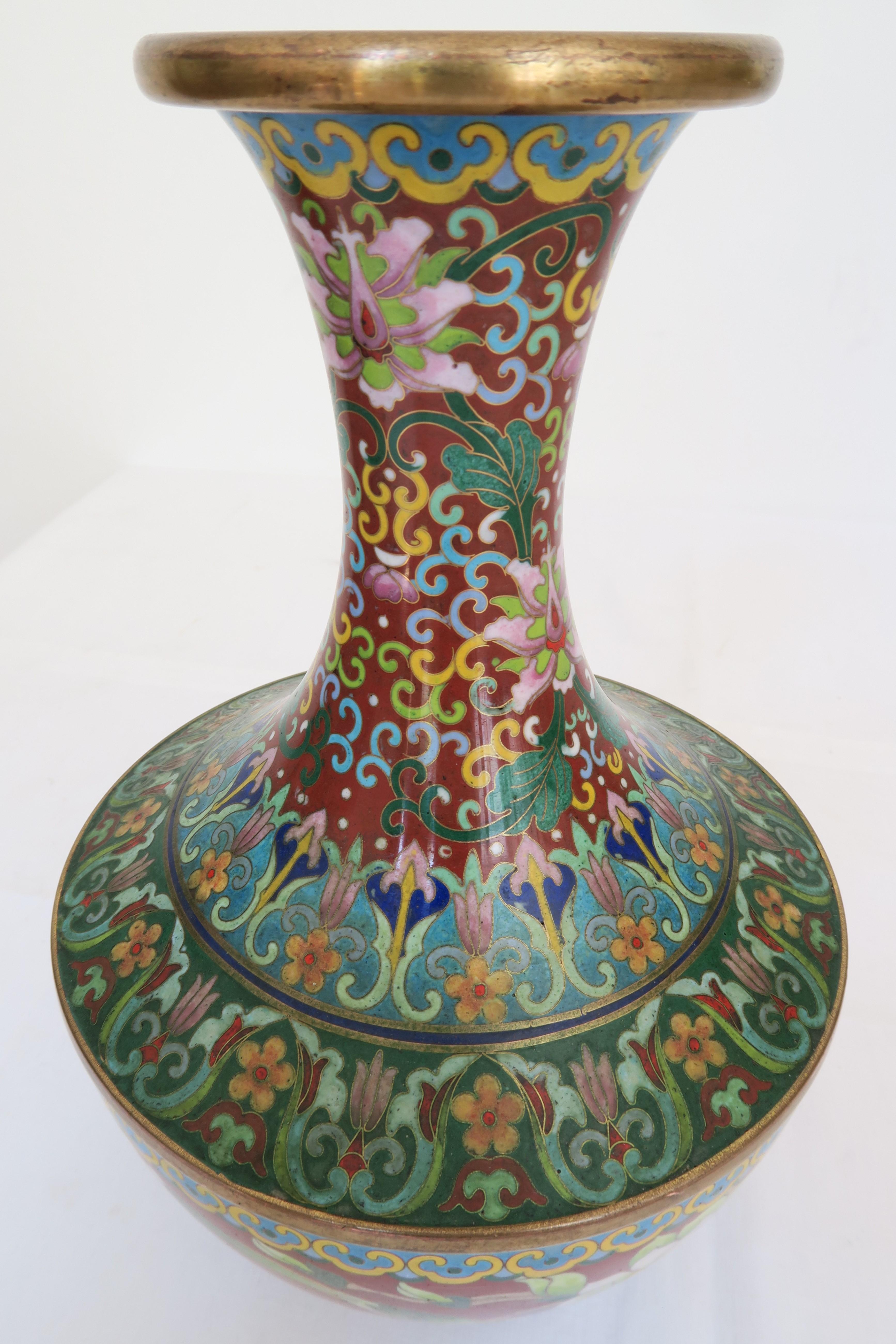 For sale is a cloisonné vase from the late Quing Dynasty (1644-1912). The bulbous walling is embellished with different colour birds, cherry- and apple blossoms over waves and generous floral ornamentation. On the neck of the vase one can also find