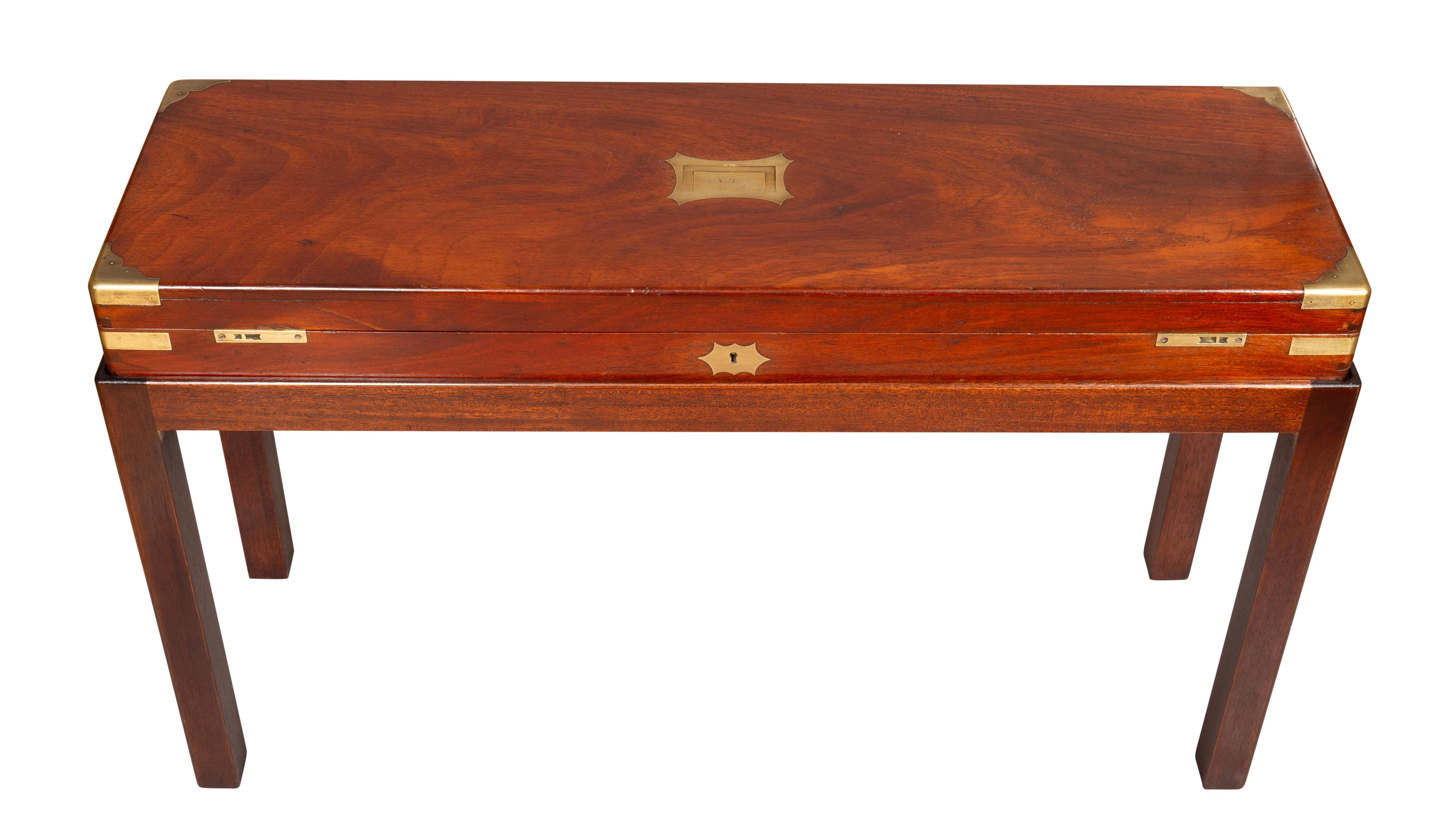 Rectangular hinged box opening to a baize lined interior. The box fitted with brass corners and central flush brass handle. Later mahogany base with square section legs.