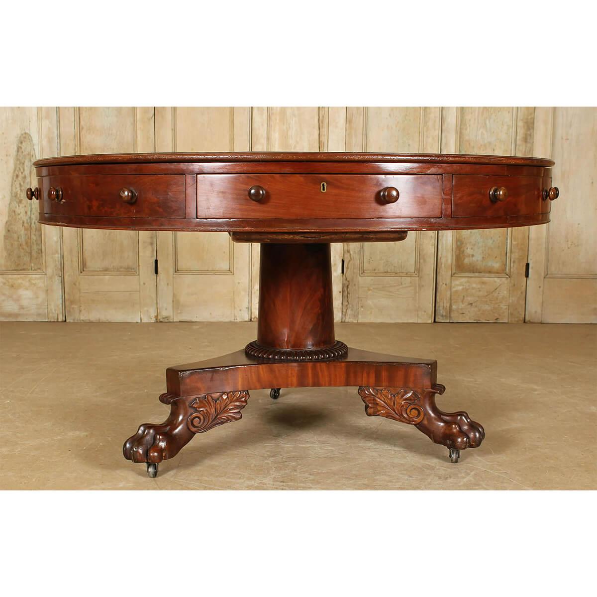 A large late Regency mahogany round drum table with a gilt-tooled leather top, frieze drawers raised on a center pedestal column, and carved lion winged paw feet. Ca 1820

Dimensions: 52.5