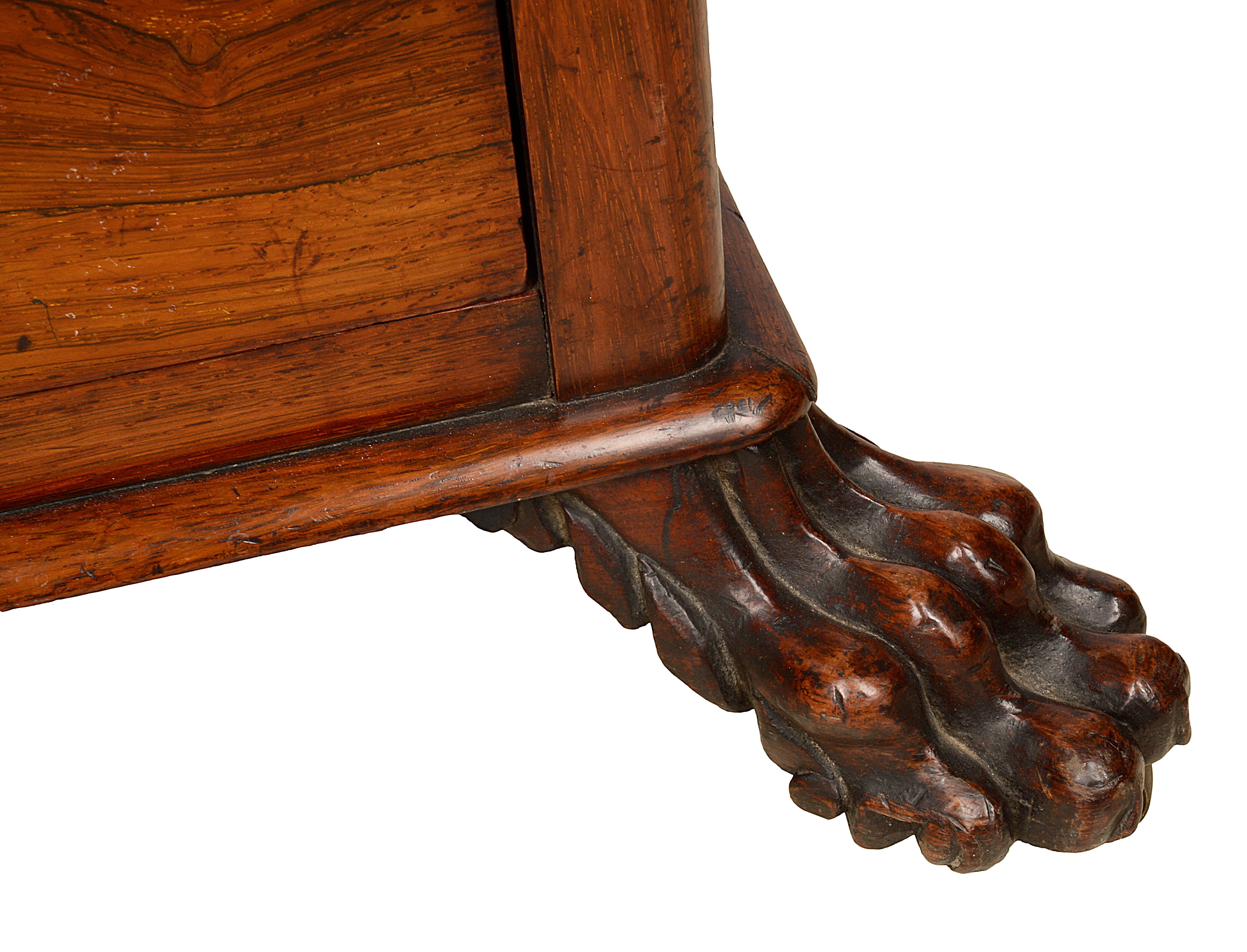 A very good quality late Regency period rosewood Canterbury music / magazine stand, having carved and pierced lyre shaped divisions, a single drawer and raised on claw feet.