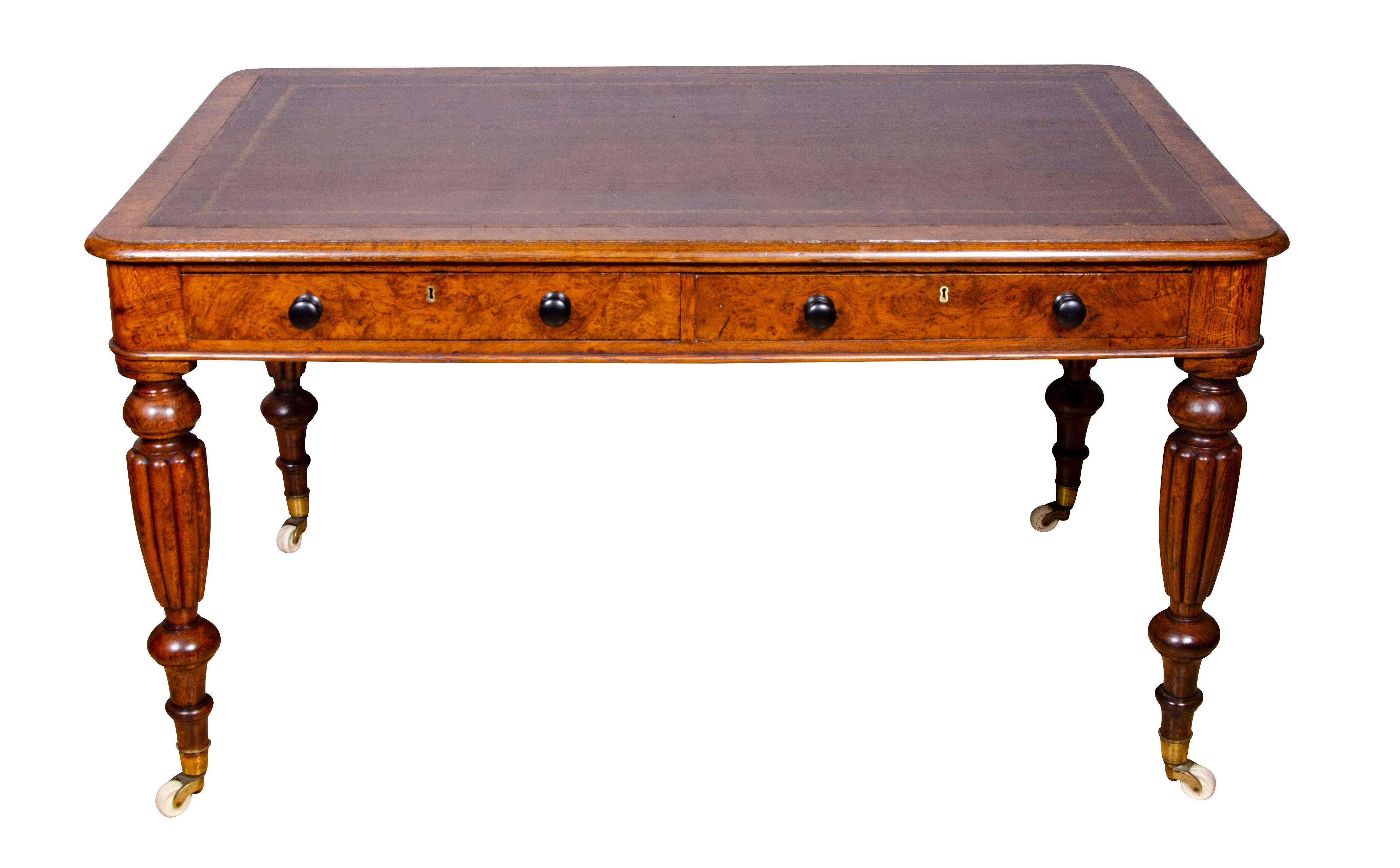 Rectangular with brown leather set in with framed border and rounded edge over two drawers with wood knobs, same configuration on reverse, raised on turned reeded legs ending on casters.