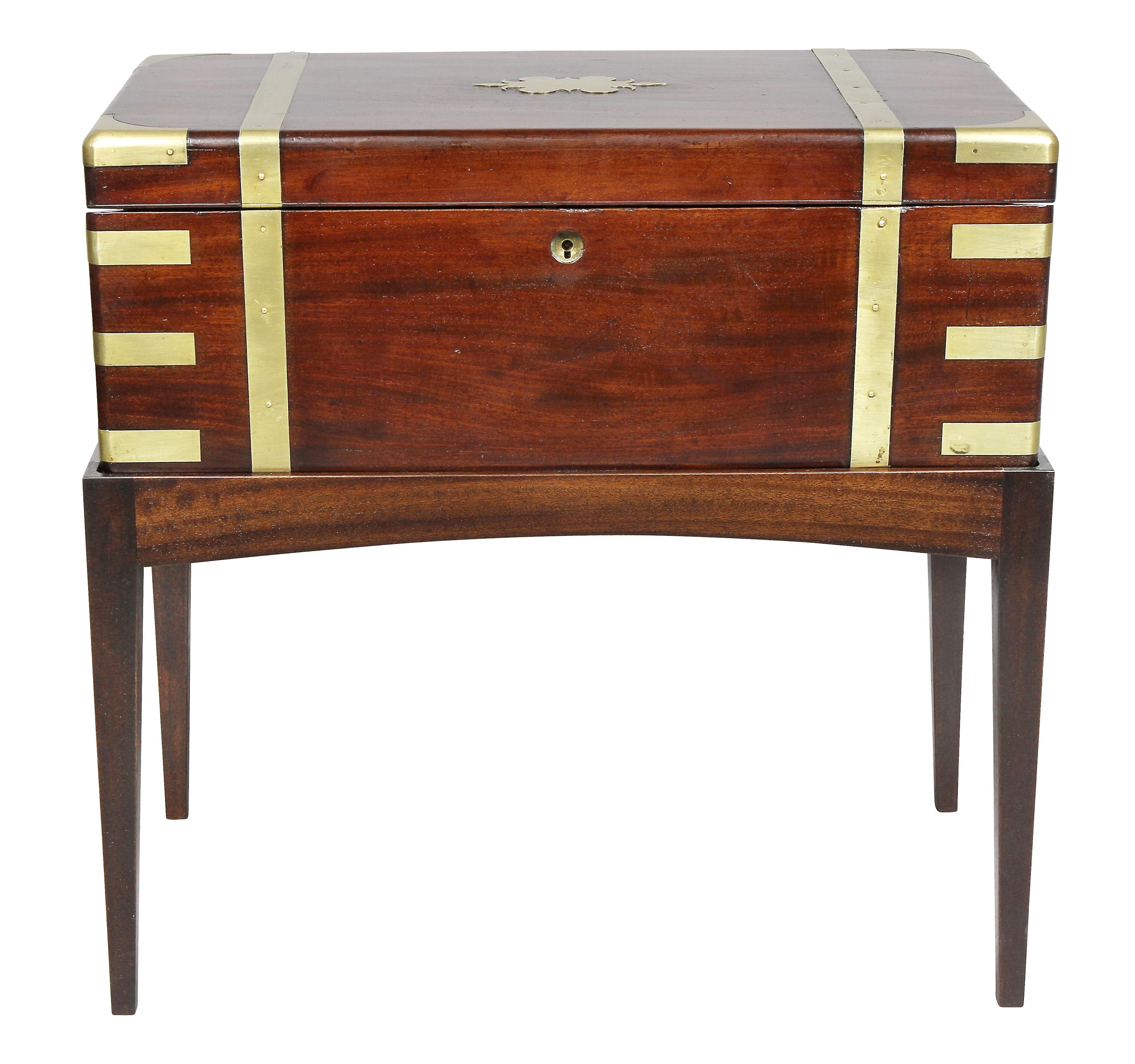 Typical form mounted with brass details and strapping, hinged top fitted with desk interior, later mahogany base.