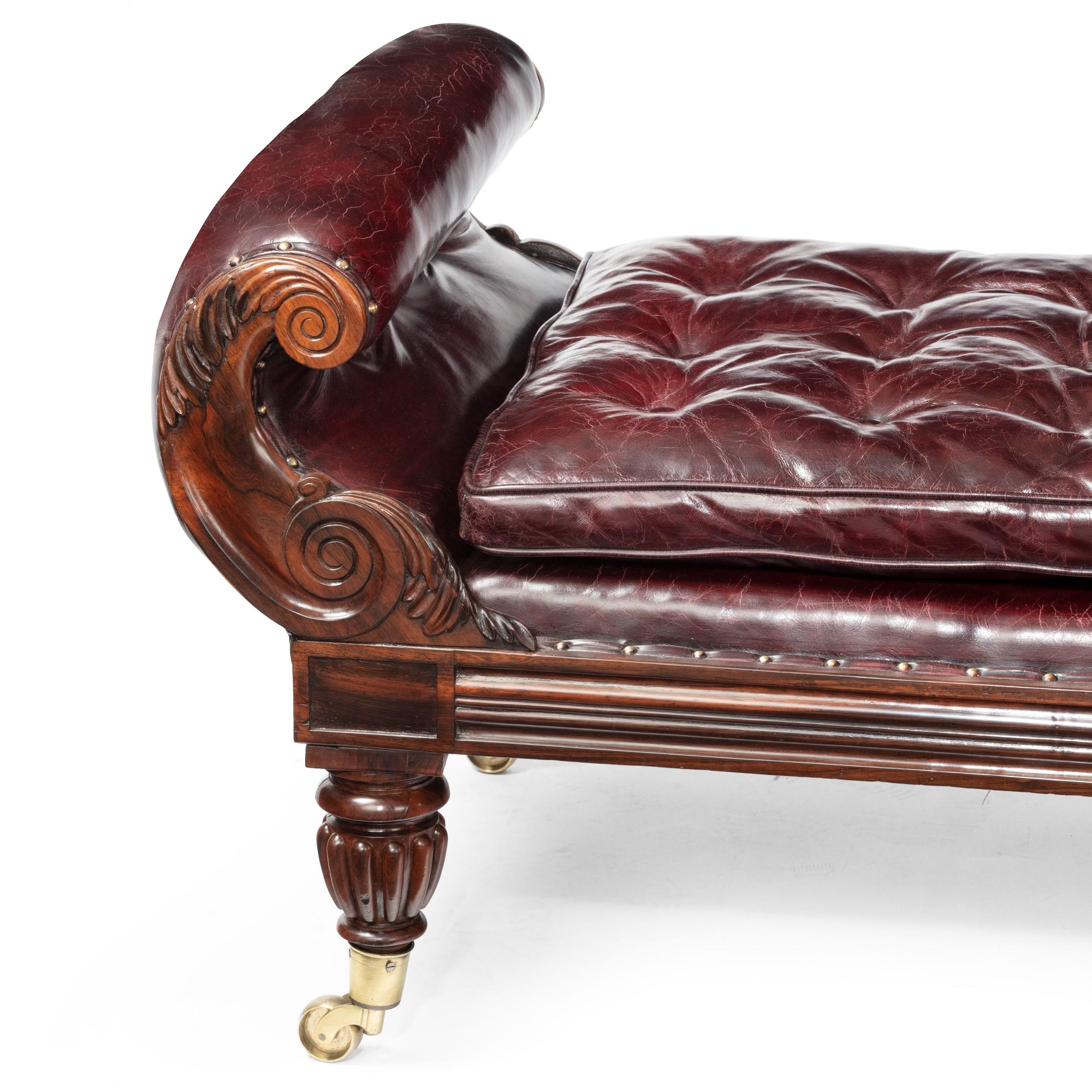 A late Regency rosewood chaise longue, with acanthus carved scroll terminals and arms, on boldly gadrooned tapering legs with the original brass castors, re-upholstered in distressed deep-buttoned burgundy leather, English, circa 1820.
 