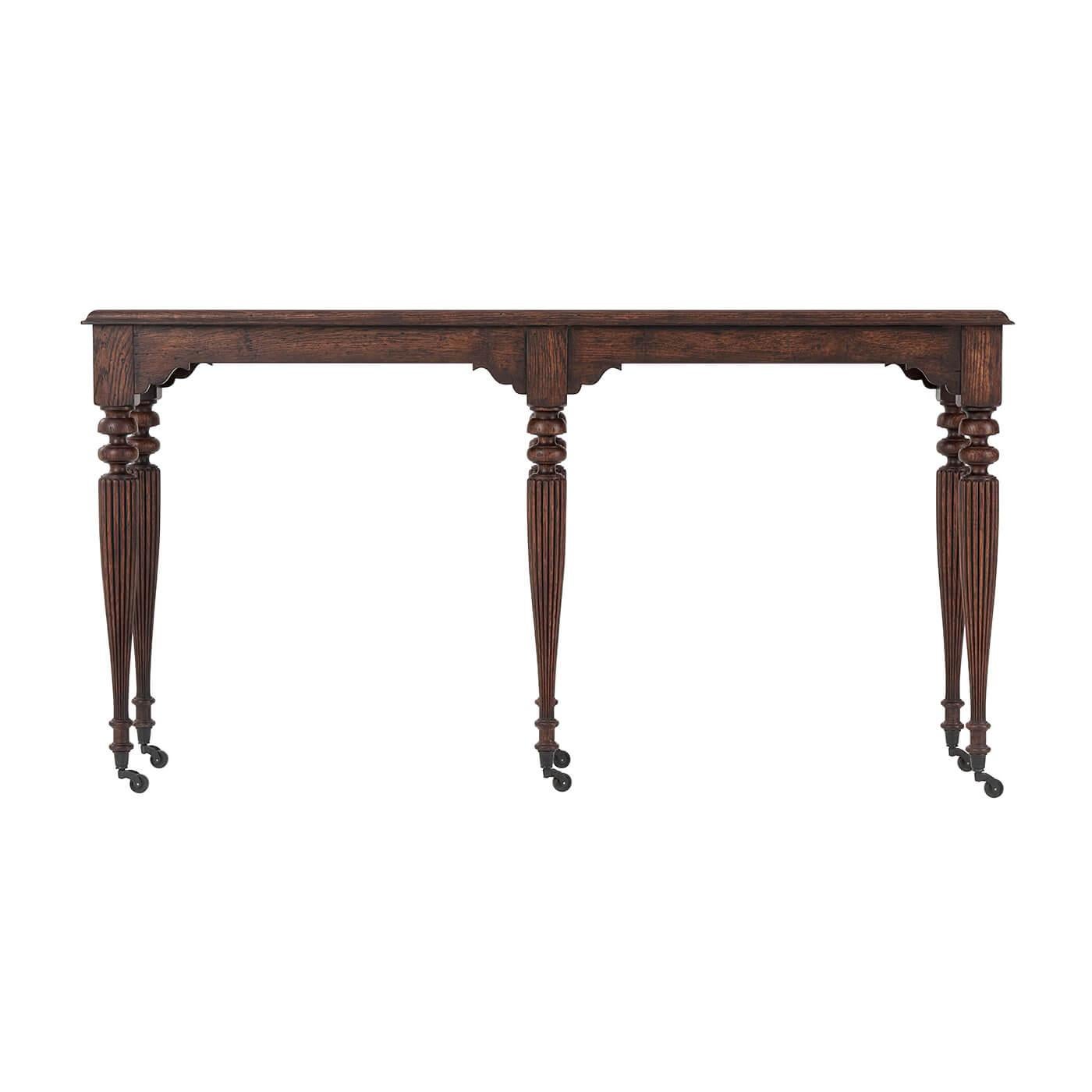 A late Regency style solid oak and reclaimed oak veneered console table, the planked and molded edge top with a bracketed apron, on six slender turned and tapered legs with reeded decoration, terminating in bronzed cappings and castors. Inspired by