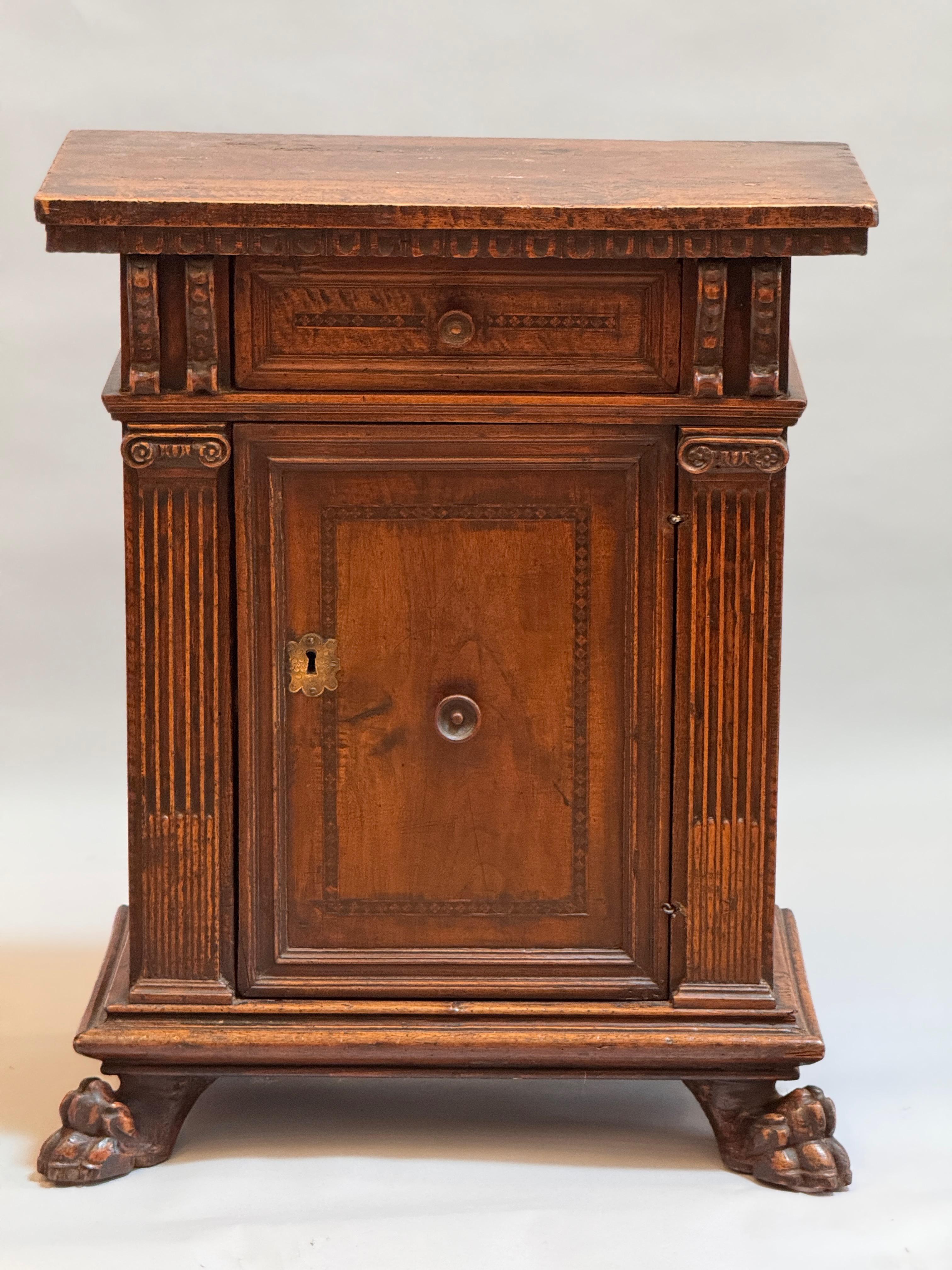 Realizzato in noce circasso con una ricca patinatura e una brillante profondità di colore.
Un cassetto singolo sopra un'anta singola dell'armadio sopra a modanature intagliate e piedi a 