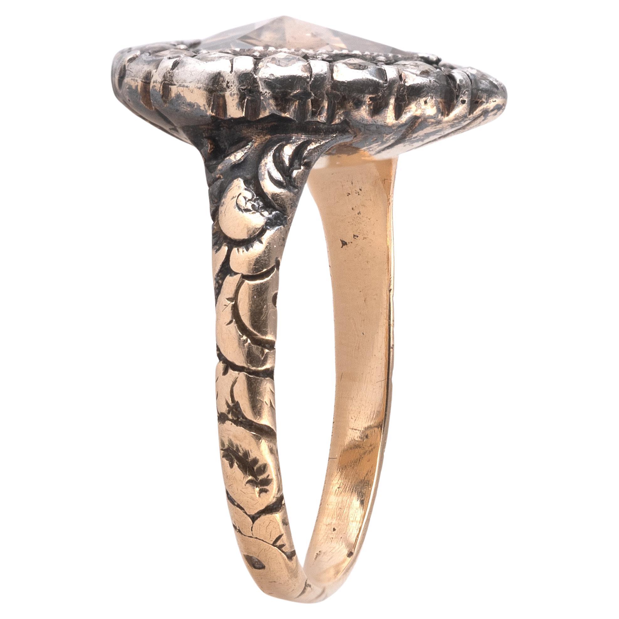 A diamond ring, designed as a pear-shaped cluster, set with rose-cut diamonds in closed-back settings, to a band carved with floral motifs, mounted in silver and gold.
Size 6 1/2
Weight: 3.3gr.
