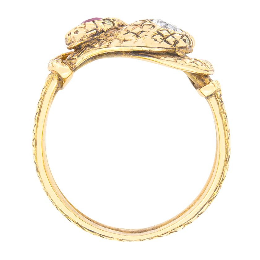 Dating to the Victorian era, this intricate ring is formed of two snakes intertwined together. Set atop each snake head is a different gem. On one, an old cut diamond weighing 0.25 carat is sat, whilst on the other is adorned with a 0.25 carat ruby.