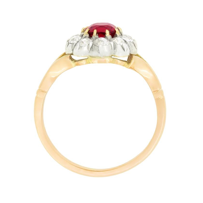 A stunning natural red spinal takes centre stage in this Late Victorian cluster ring. The 0.90 carat stone is oval cut and exudes a vibrant red colour. Surrounding the gem, a total of 0.50 carat in old mine cut diamonds are set into platinum. The