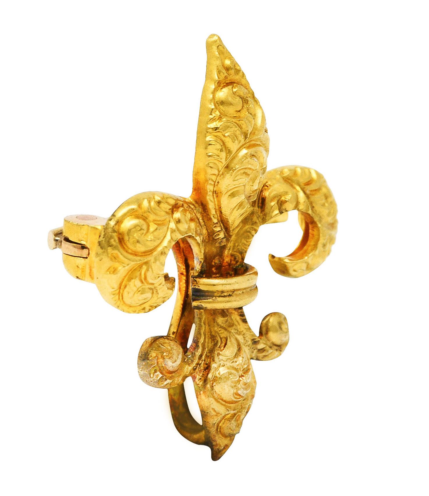 Pendant brooch designed as stylized fleur-de-lis symbol

Featuring engraved curling plumes

With ridged central banding

Completed by hinged pin stem and looping bale for optional drop, watch or locket

Stamped 14k for 14 karat gold

Circa:
