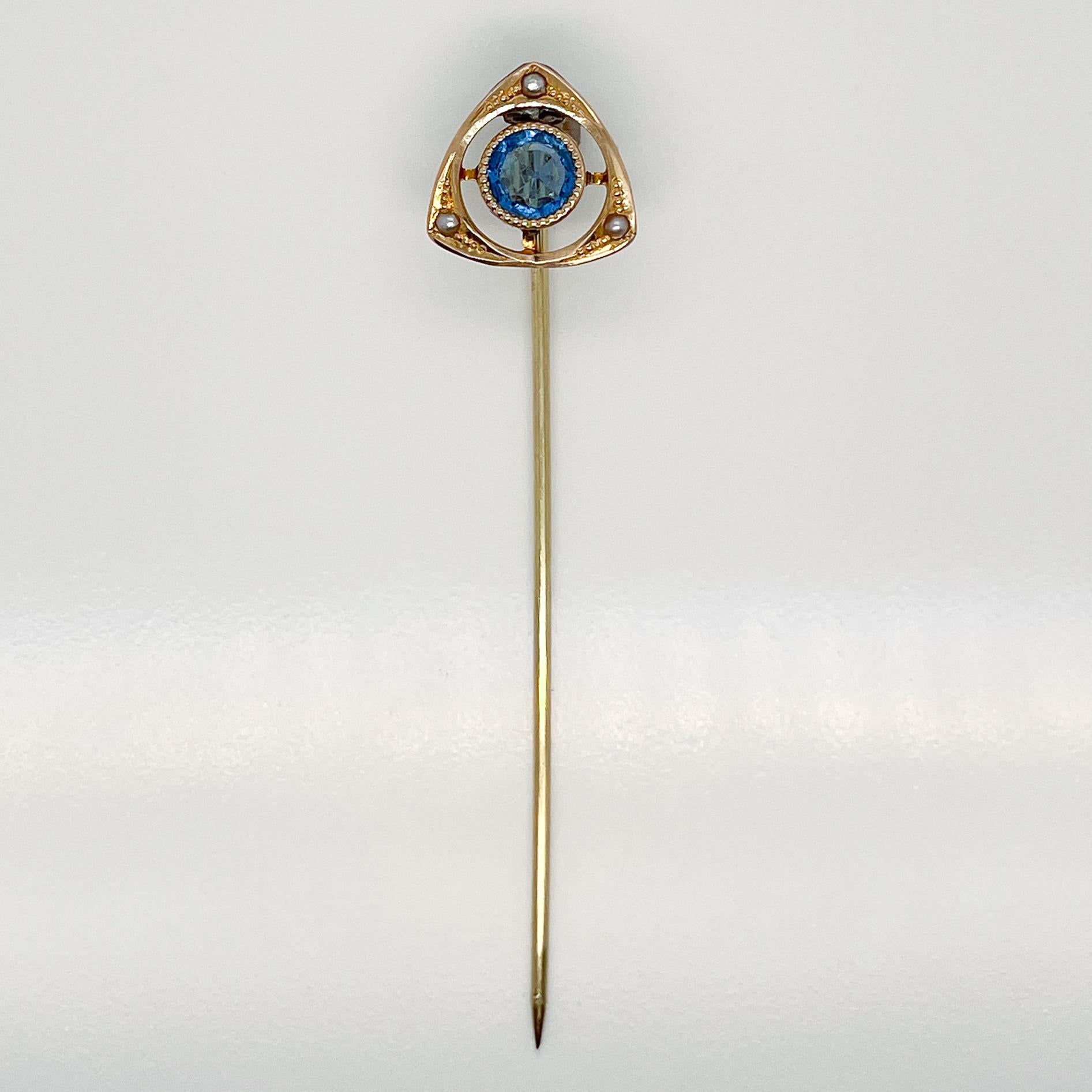 A very fine Late Victorian 14k gold, glass cabochon and seed pearl stick pin.

With a round blue glass cabochon at the center of 14k gold triangular head and framed by three seed pearls flush set on each corner set on a later 14k pin stem.

Simply a