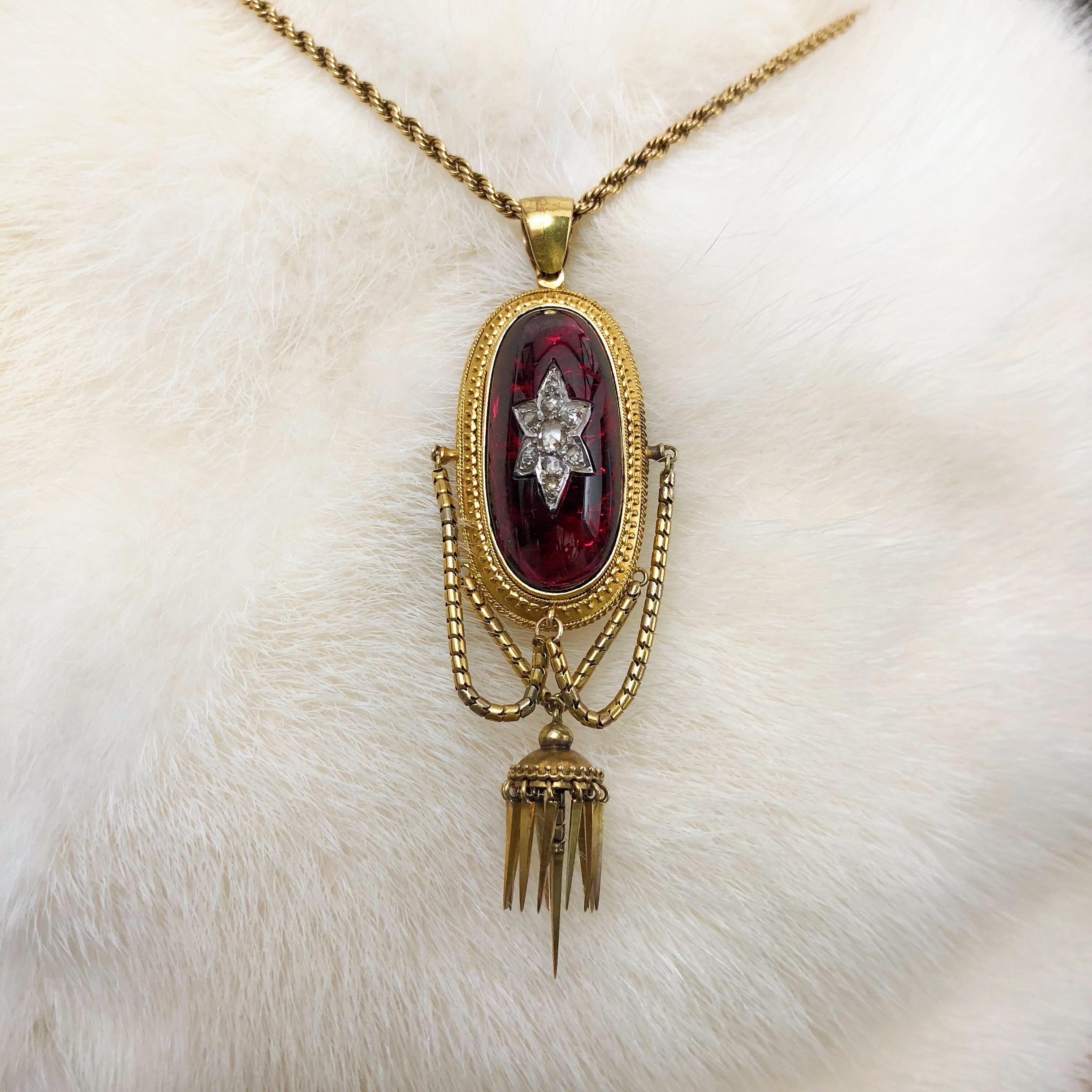 A late Victorian 18ct gold garnet and diamond pendant. Comprising a rose-cut diamond star, inset to the foil back oval garnet cabochon, with swag and tassel, suspended from a rope-twist chain. Length of pendant 7.4cms. Length of chain 48cms. Weight