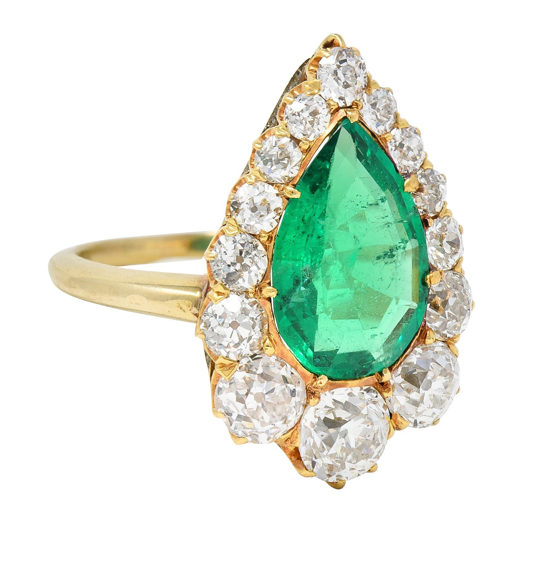 Centering a pear-shaped step-cut emerald weighing 2.41 carats - transparent medium green in color 
Natural Colombian in origin and displaying with minor traditional treatment (F2)
Prong set with a halo surround of graduated old mine and European cut