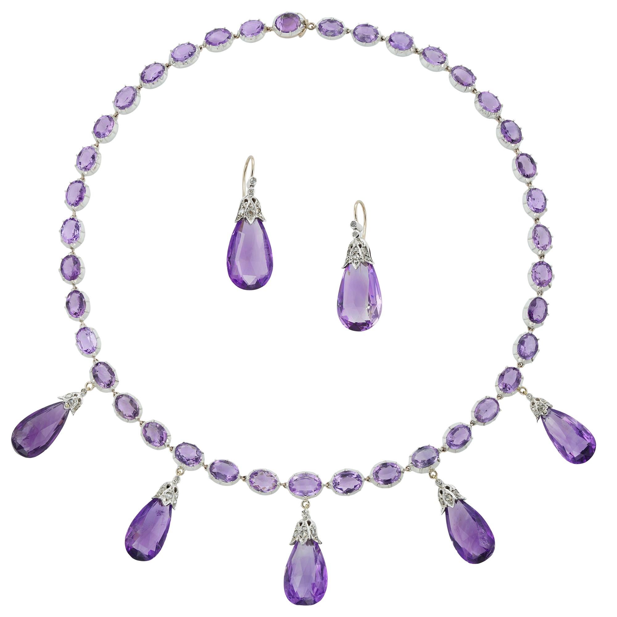 A late Victorian amethyst necklace and earrings, the necklace consisting of thirty-nine oval faceted amethyst, all set in cut-down collets, suspending five pear-shaped briolette-cut amethyst drops each with diamond-set cap of foliate design, all