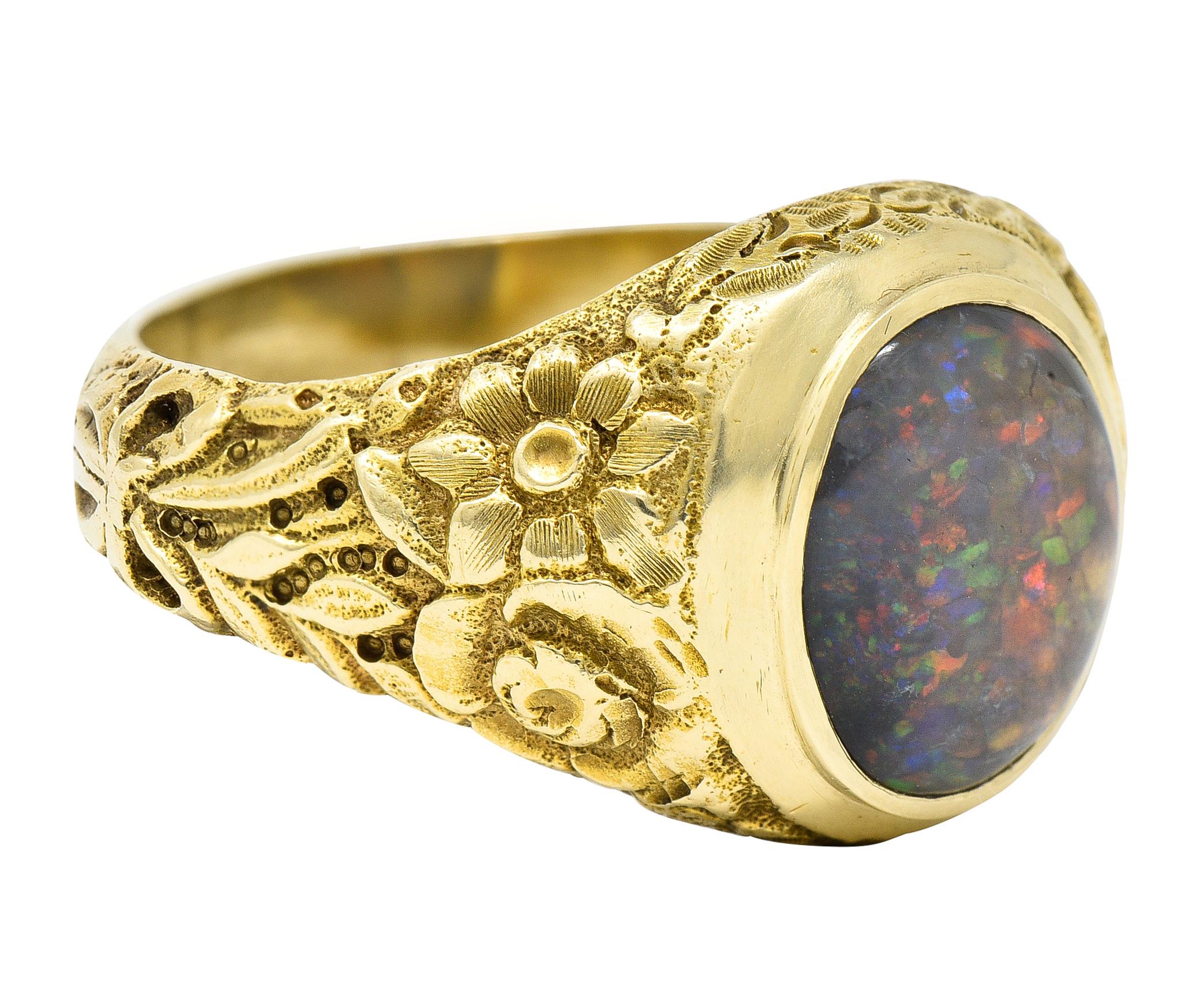 Signet style band ring centers an oval black opal cabochon measuring approximately 12.0 x 10.0 mm

Translucent gray in body color with strong and spectral play-of-color

Bezel set in a polished gold surround with a highly rendered shank

Depicting