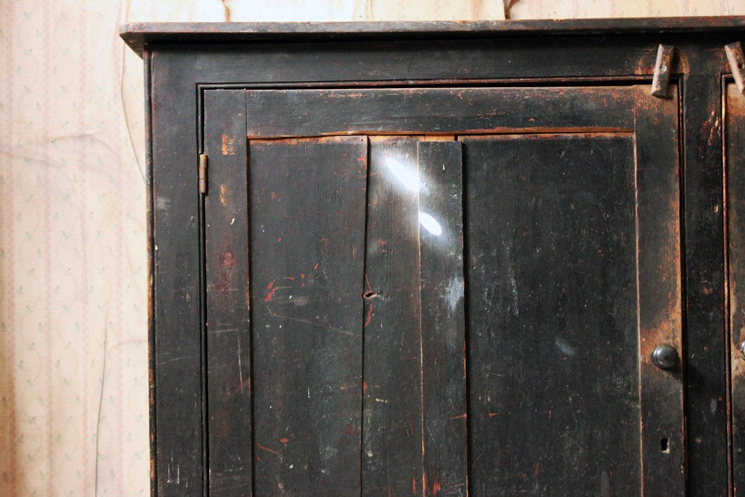 The late Victorian period pine carcass of relatively large size, formerly having been used as a food or larder cupboard with one flank being air ventilated with mesh, the other being panelled, showing the original period black painted finish now