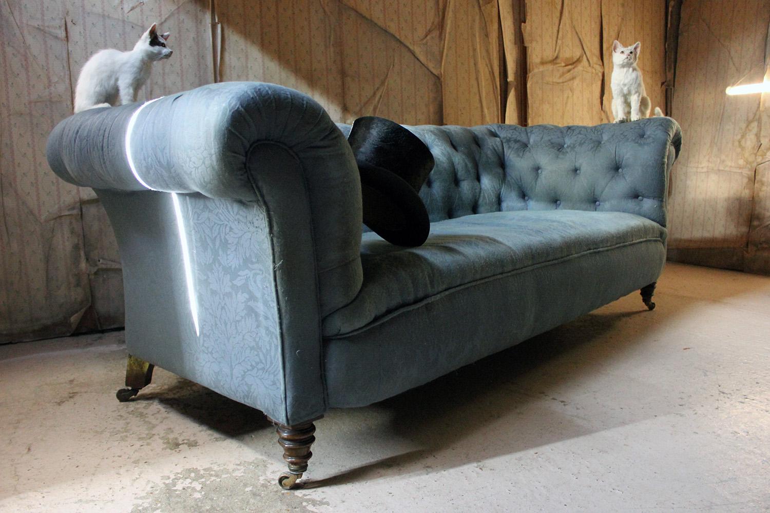 The three-seat country-house quality carcass with sprung seat, the whole being button-backed and upholstered in a peacock blue William Morris type floral fabric with single piping, though tired and dirty it is prime for recovering, the whole sitting