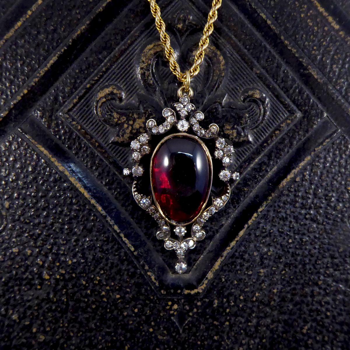 This gorgeous quality antique pendant holds a large closed back collar set Cabochon Garnet with such a deep red colour to it. It has a decorative surround of small Old Cut Diamonds with a Silver top and Gold back. It is a lovely example of a antique