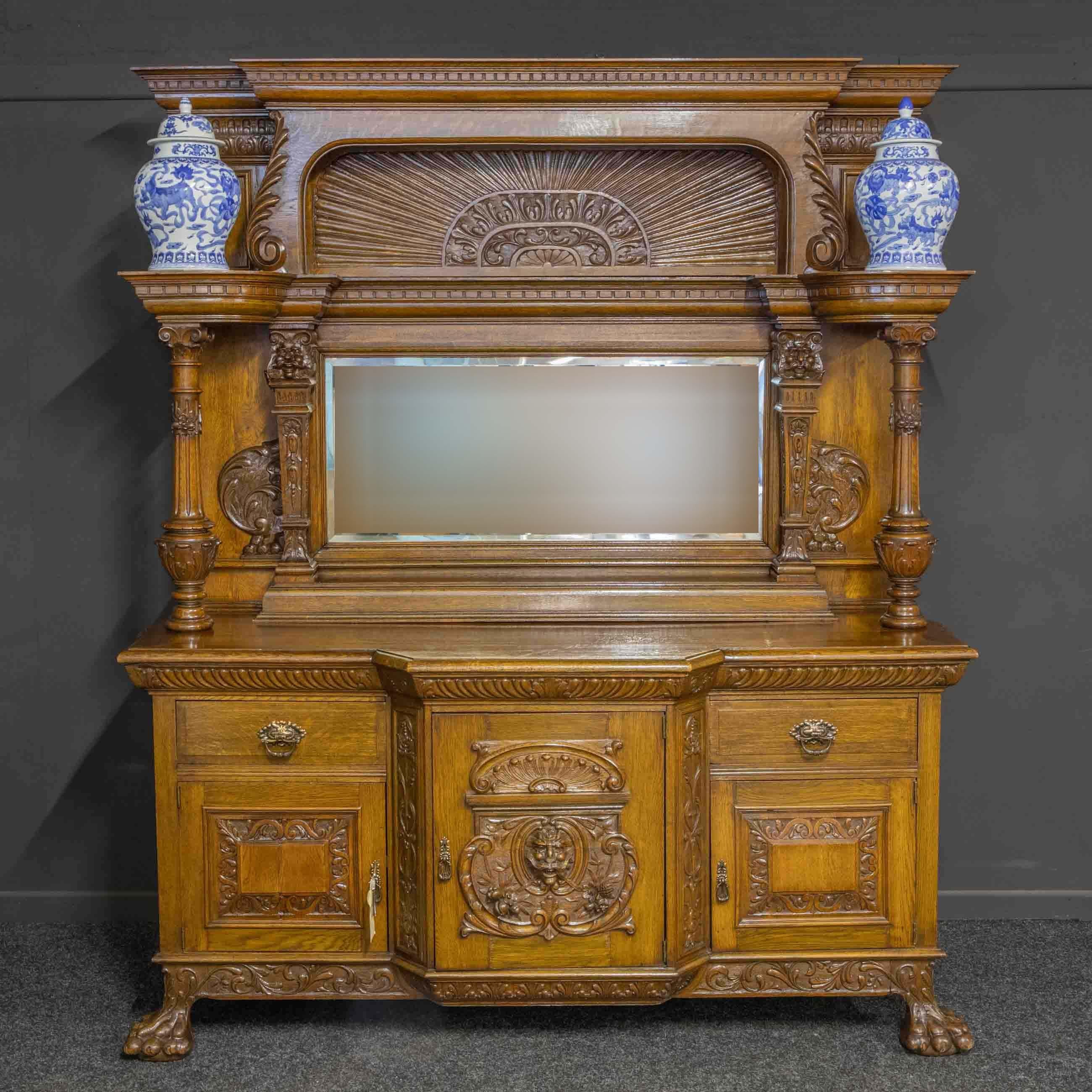 A monumental late Victorian oak sideboard of impressive size and quality. Of unusual design with large clawed feet that splay outwards to the side and front, above which is a crisply carved lower apron supporting three cupboards (with working locks