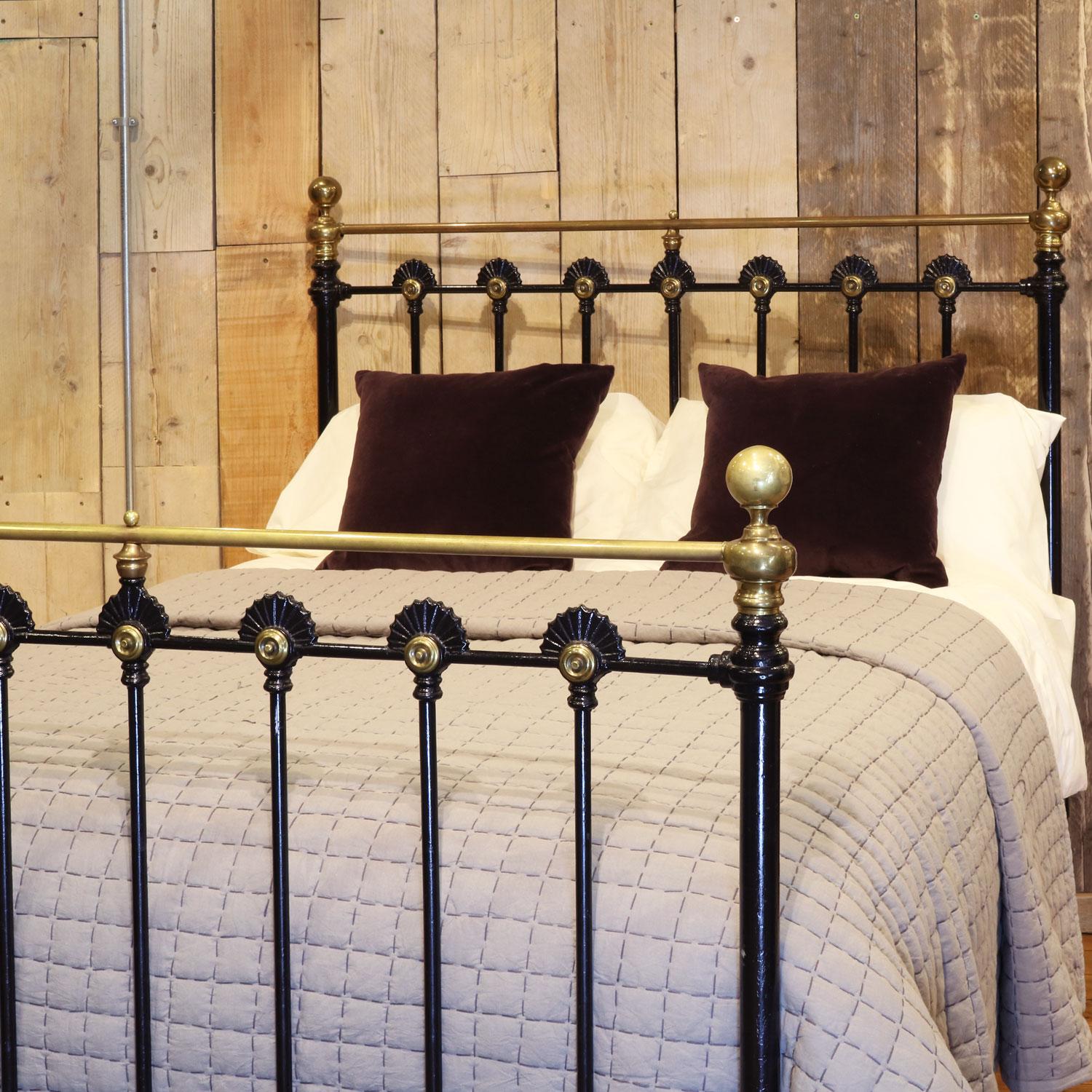 Late Victorian brass and cast iron bedstead, finished in black with straight brass top rail and stunning brass rosettes upon iron castings on the head and foot boards. 

This bed accepts a double size 4ft 6in wide (54 inch or 135cm) base and